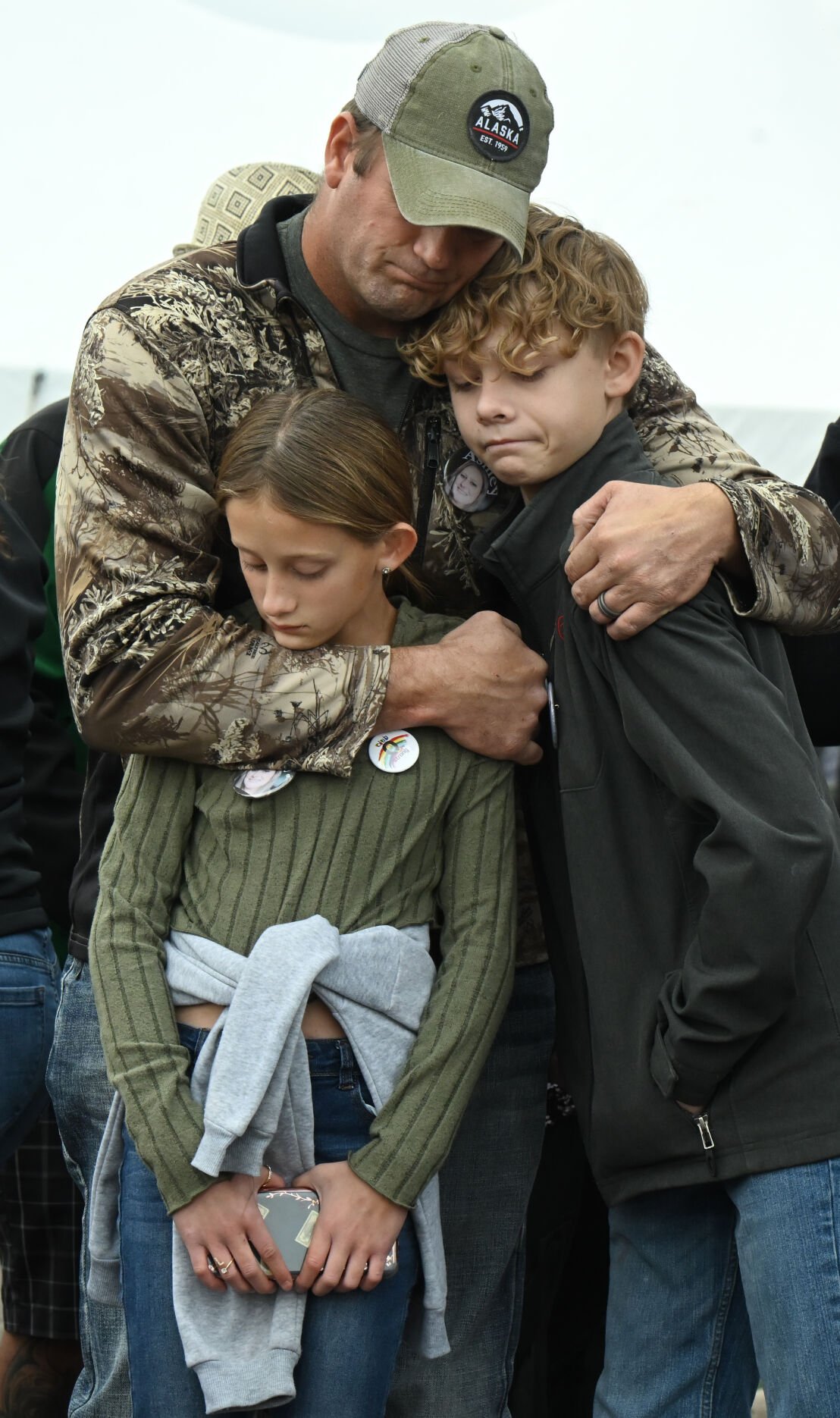 Brayson Hochevar (right) and his sister, Alexis Clark, get hugs from their father during a memorial service for their aunt, Ashley Paugh, one of the victims of the Club Q shooting. A memorial was held outside of the now closed Club Q, marking the one-year anniversary of the mass shooting on Sunday, Nov. 19, 2023. A year ago, Kelly Loving, Derrick Rump, Ashley Paugh, Raymond Green Vance and Daniel Aston were killed in the nightclub shooting and 17 were injured. (Photo by Jerilee Bennett, The Gazette)