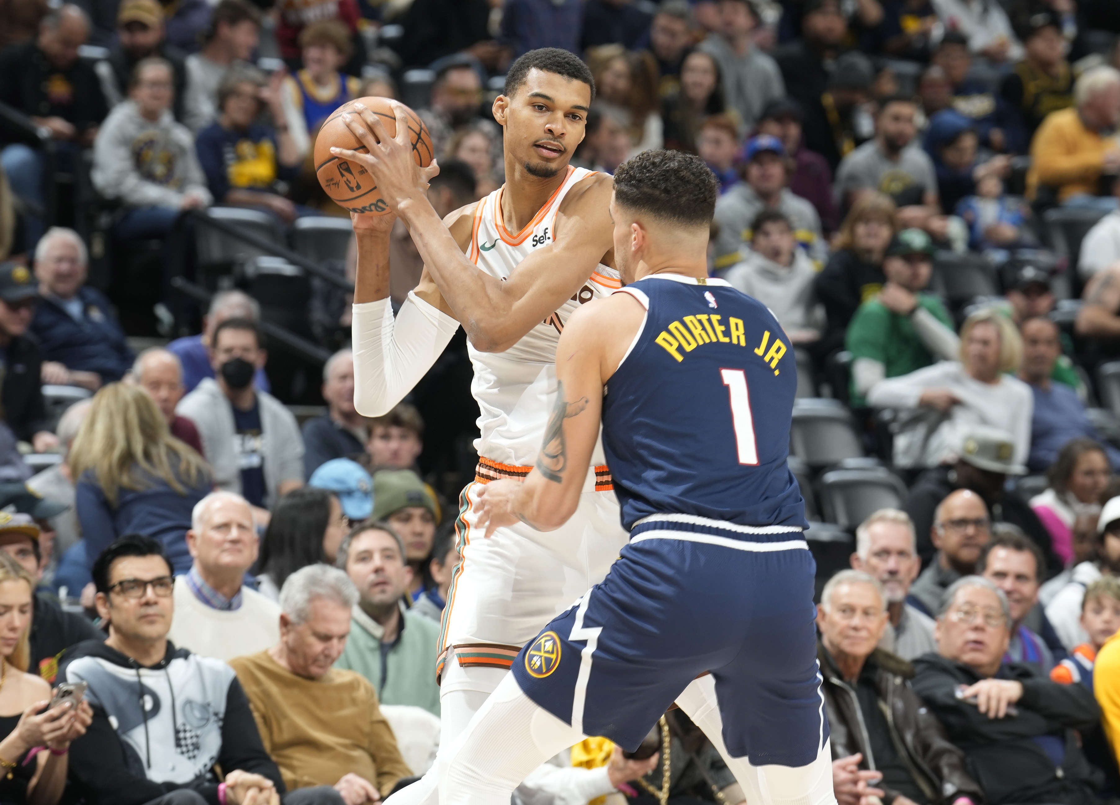 San Antonio Spurs center Victor Wembanyama, left, looks to pass the ball as Denver Nuggets forward Michael Porter Jr., right, defends in the first half of an NBA basketball game Sunday, Nov. 26, 2023, in Denver. (AP Photo/David Zalubowski) (David Zalubowski)