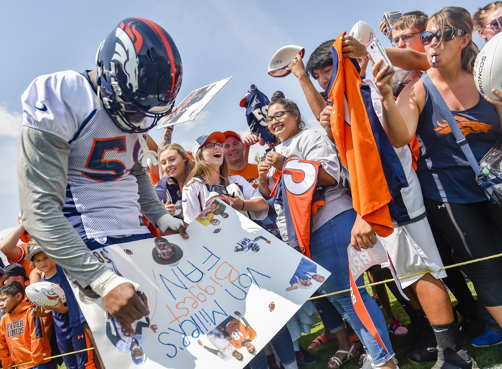 Ever the fan favorite, Von Miller, (58), left, signs a huge sign by Adriana Batres, center, of Colorado Springs following the team's first day of practice at the UCHealth Training Center on Saturday July 28, 2018 in Englewood.(Photo by Dougal Brownlie, The Gazette). (Dougal Brownlie, The Gazette)