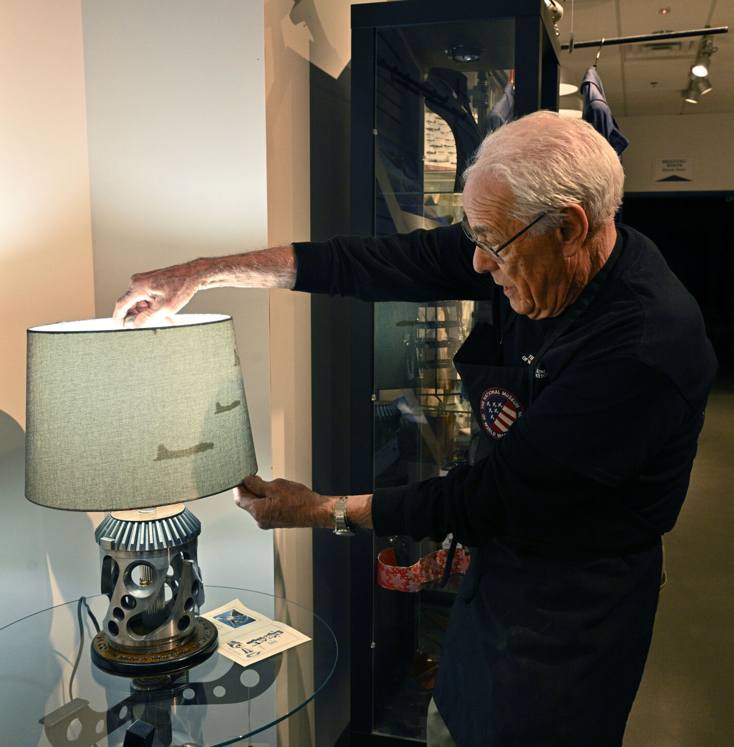 Bill Ballard displays a lamp made from using the repurposed parts of a WWII plane at the National Museum of World War II Aviation Museum gift shop. (jerilee bennett, the gazette)