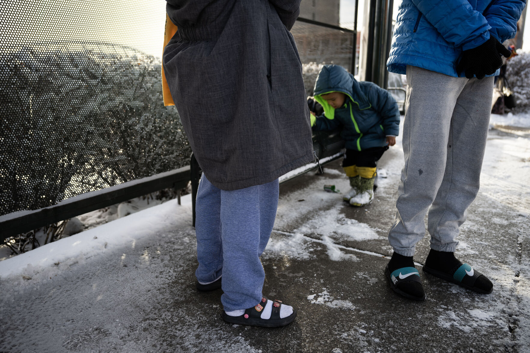 A family of newly-arrived immigrants from Venezuela wear only socks and sandals on their feet, and jackets provided by a local contact, after being dropped off by an overnight bus from El Paso, Texas early Saturday morning, after an overnight snowstorm on Dec. 9, 2023, in Denver, Colo. (Timothy Hurst/Denver Gazette) (TimHursttim.hurst@gazette.comhttps://secure.gravatar.com/avatar/aca82bd62b4ee425c598527cd6faa1b1?d=mm&r=g)