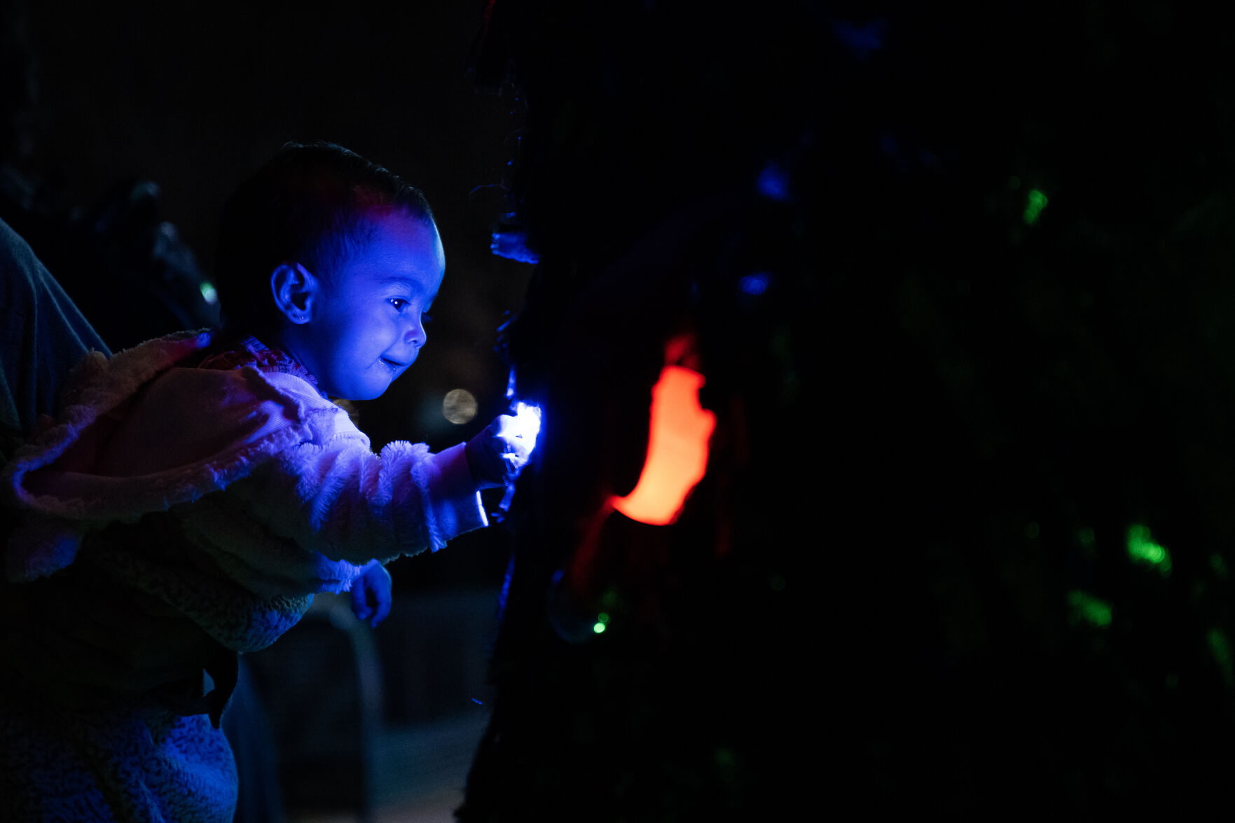 Raven Martinez, 1, reaches out to touch the lights on one of the two dancing trees making their way through the crowd during the city of Aurora’s annual Holiday Tree Lighting on Tuesday, Dec. 5, 2023, at the Aurora Municipal Center. (Timothy Hurst/Denver Gazette) (TimHursttim.hurst@gazette.comhttps://secure.gravatar.com/avatar/aca82bd62b4ee425c598527cd6faa1b1?d=mm&r=g)