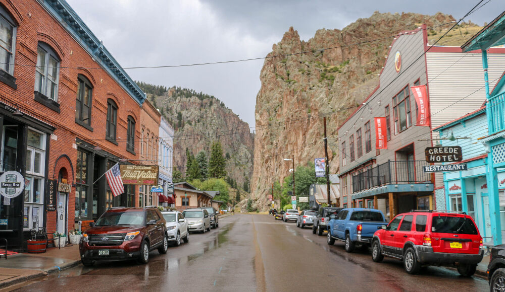 Main Street in Creede ends at the base of a cliff that extends 1,000 feet higher than the town's already 9,000-foot elevation. That's the original Creede Repertory Theatre on the right, behind the Creede Hotel. The theater has been the central gathering spot in Creede for 57 years. In 2011, the company opened a second theater further down the street, called The Ruth. Photo taken Aug. 24, 2023. (John Moore, Denver Gazette)