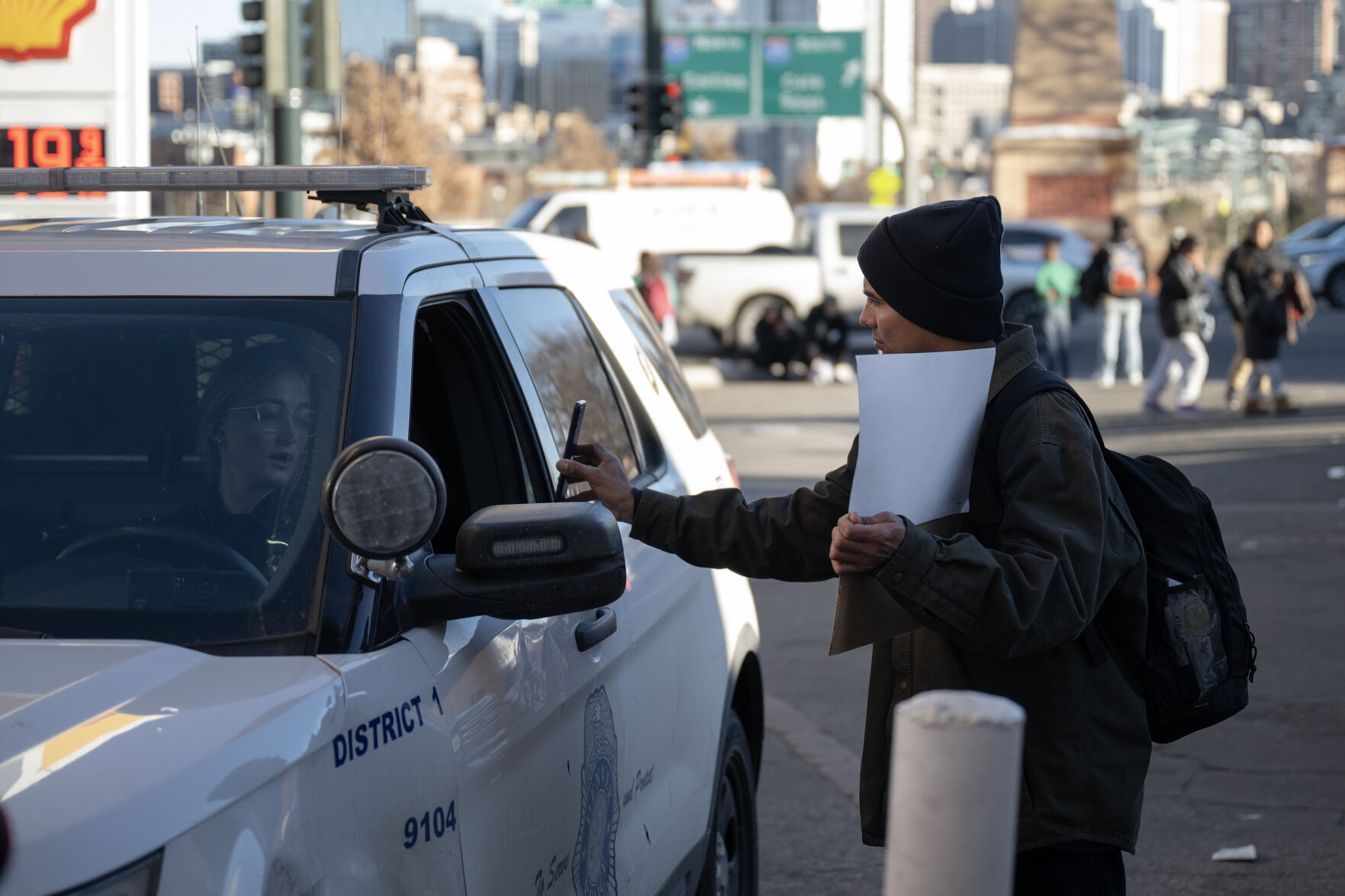 ABOVE: A migrant uses his phone to translate and ask a Denver police officer if there’s a problem with his holding a sign expressing his desire to work in front a gas station around the corner from a migrant encampment at West 27th Avenue and Zuni Street. (TimHursttim.hurst@gazette.comhttps://secure.gravatar.com/avatar/aca82bd62b4ee425c598527cd6faa1b1?d=mm&r=g)