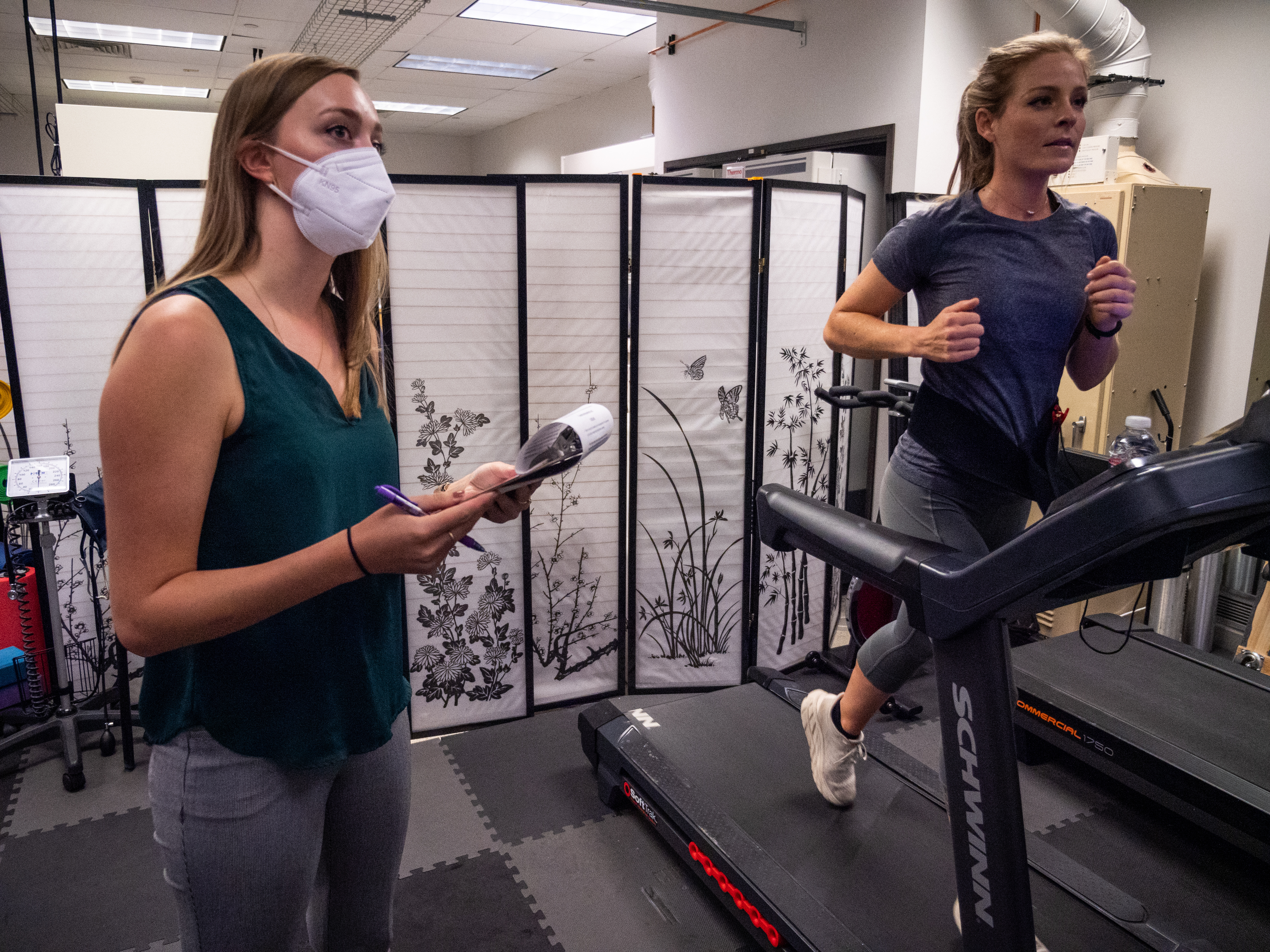 Ultrarunner Heather Mashhoodi runs on the treadmill in 2021 as part of a study exploring how cannabis influences exercise. First author Laurel Gibson takes notes in the background. Study participants used cannabis on their own at home before being picked up and driven to the lab for testing. (Courtesy photo, Patrick Campbell/CU Boulder)