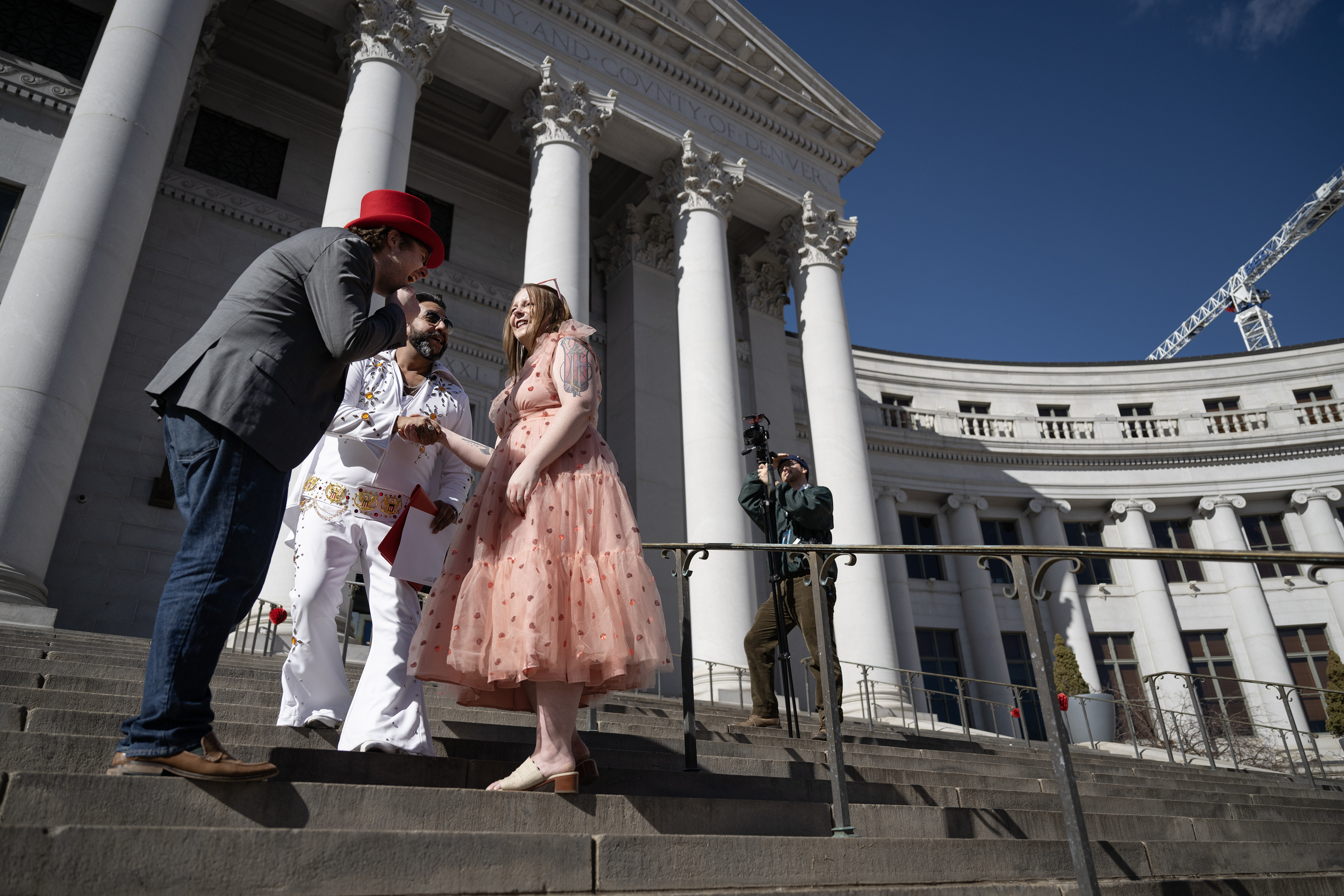 Bronson Eshleman, left, cracks up after he, his newlywed wife Julia Perry and Denver Clerk and Recorder Paul López, their officiant who is dressed as Elvis Presley for the occasion, got mixed up while everyone was attempting to shake hands following the couples’ first kiss on the steps of the Denver City and County Building during the 16th annual Marriage Marathon on Wednesday, Feb. 14, 2024, in Denver, Colo. (Timothy Hurst/Denver Gazette) (TimHursttim.hurst@gazette.comhttps://secure.gravatar.com/avatar/aca82bd62b4ee425c598527cd6faa1b1?d=mm&r=g)