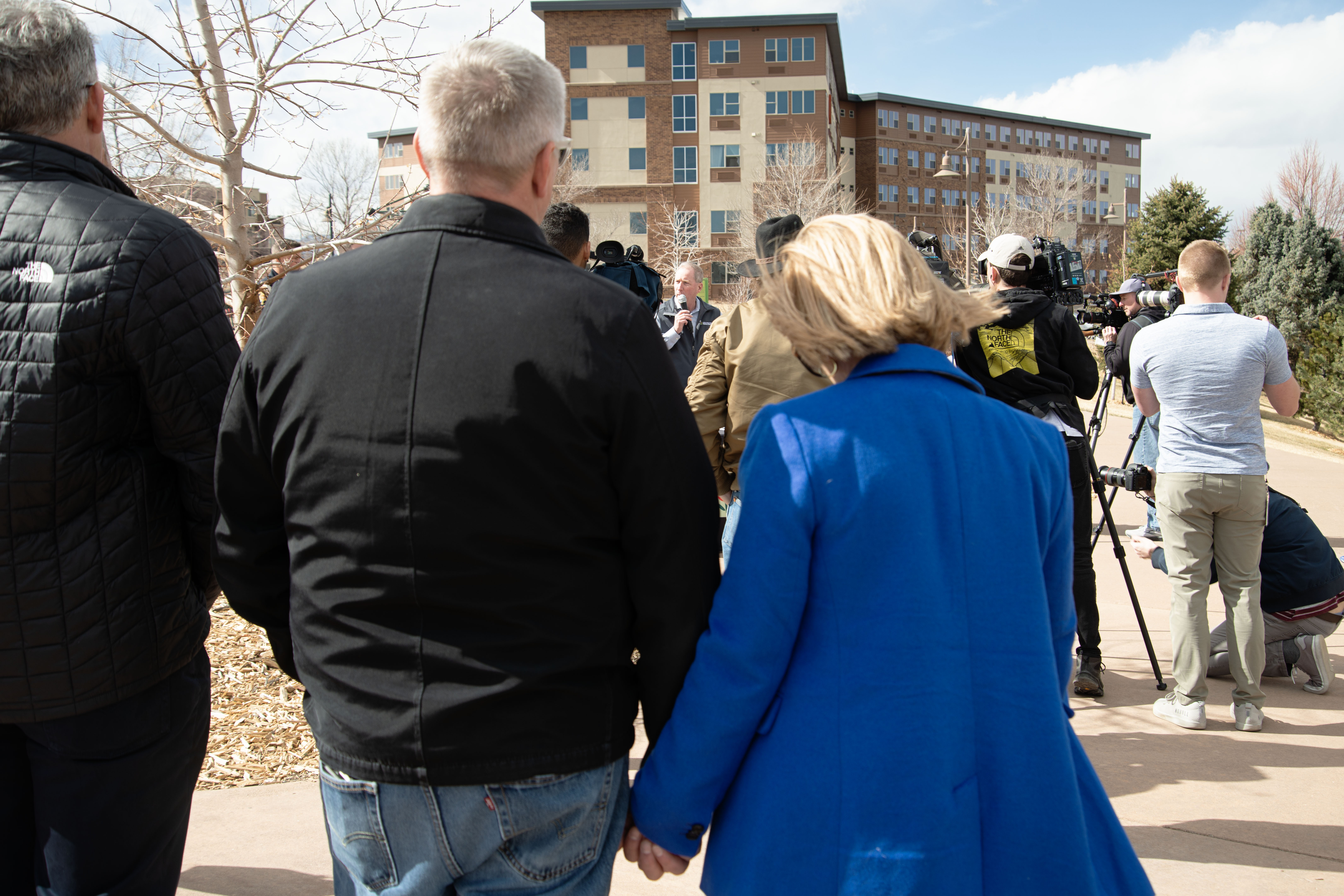 Robert, left, and Stephanie Stanley, right, hold hands while listening to speakers honor the late Kendrick Castillo in a ceremony in Civic Green Park in Highlands Ranch, Colo. on Monday, Feb. 26, 2024. 