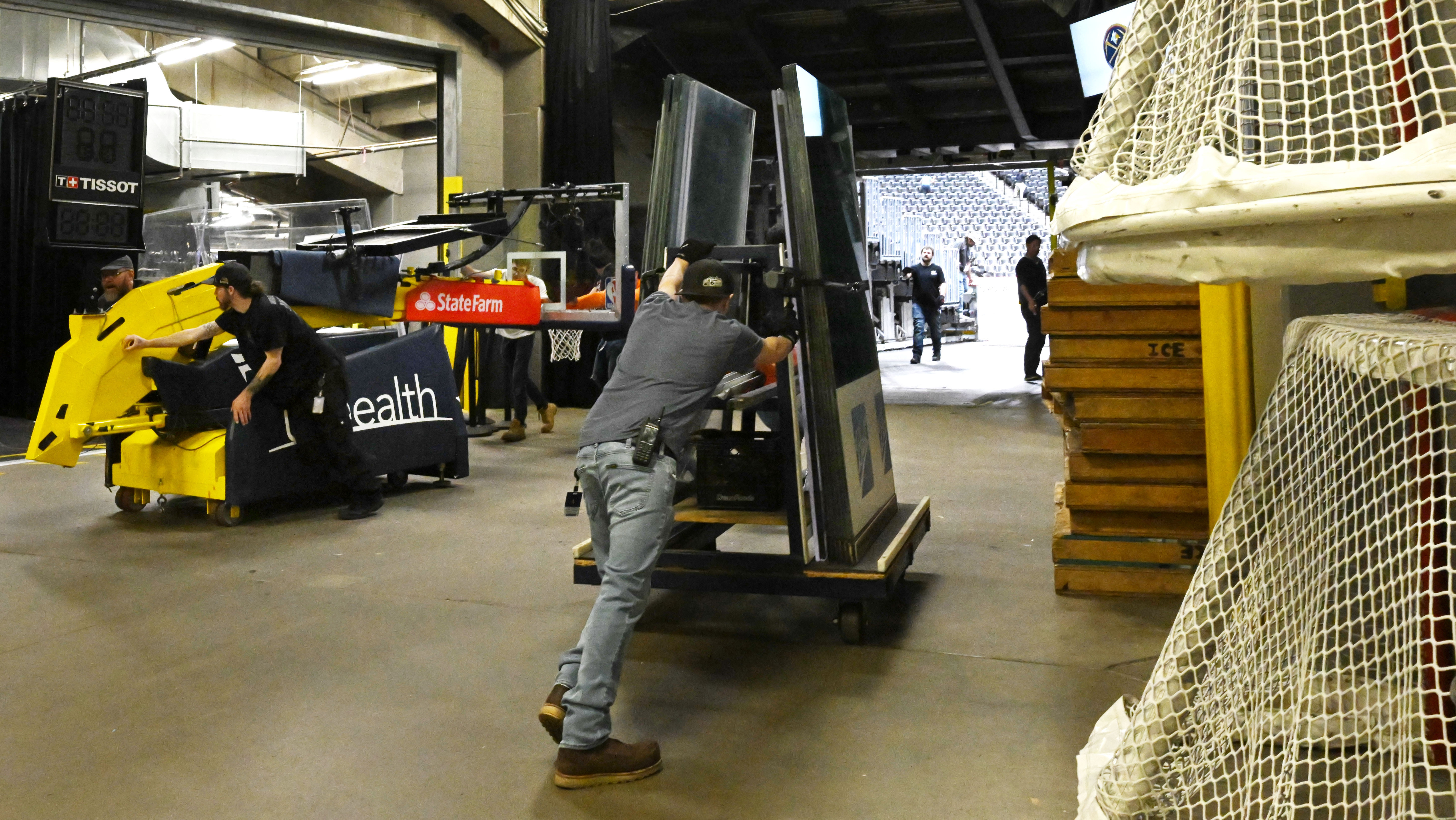 The basketball goal for the Nuggets and the glass for the rink for the Avalanche pass each other before finishing the setup for the Avalanche ice rink. Ball Arena was transformed from Nuggets to Avalanche overnight on Thursday, March 21, 2024. (Photo by Jerilee Bennett, The Gazette)
