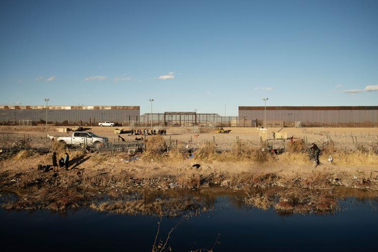 Immigrants look for ways to cross a series of recently-erected barbed wire groupings (copy)