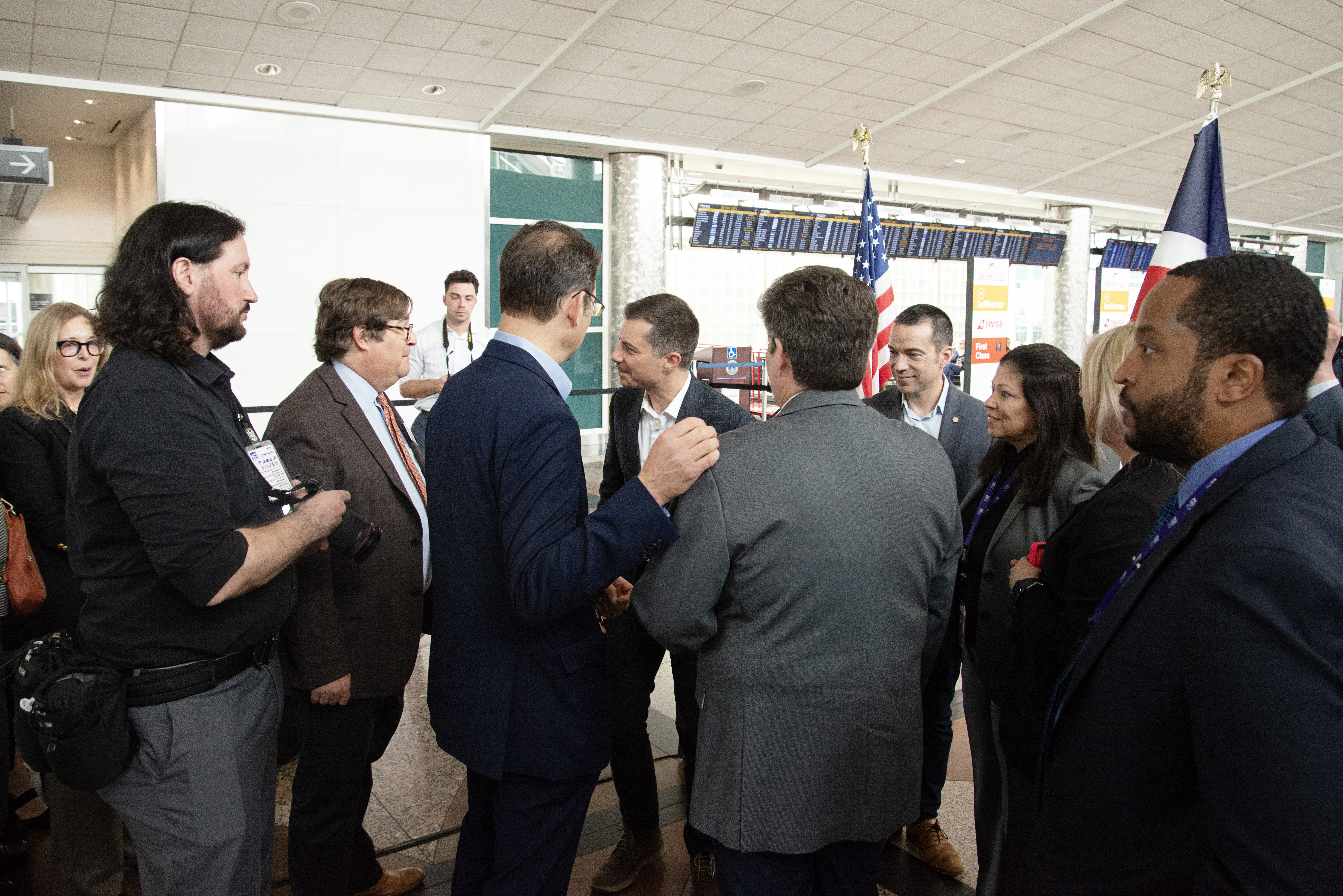 U.S. Transportation Secretary Pete Buttigieg, center, greets various Colorado officials and media present for a press conference with Colorado Attorney General Phil Weiser at the Denver International Airport on Tuesday, April 16, 2024. Buttigieg was in town for the day, showing up to the press conference with luggage in hand. After the presser, Buttigieg headed to tour infrastructure with the Governor and Mayor. One Buttigieg staffer joked on the short trip,