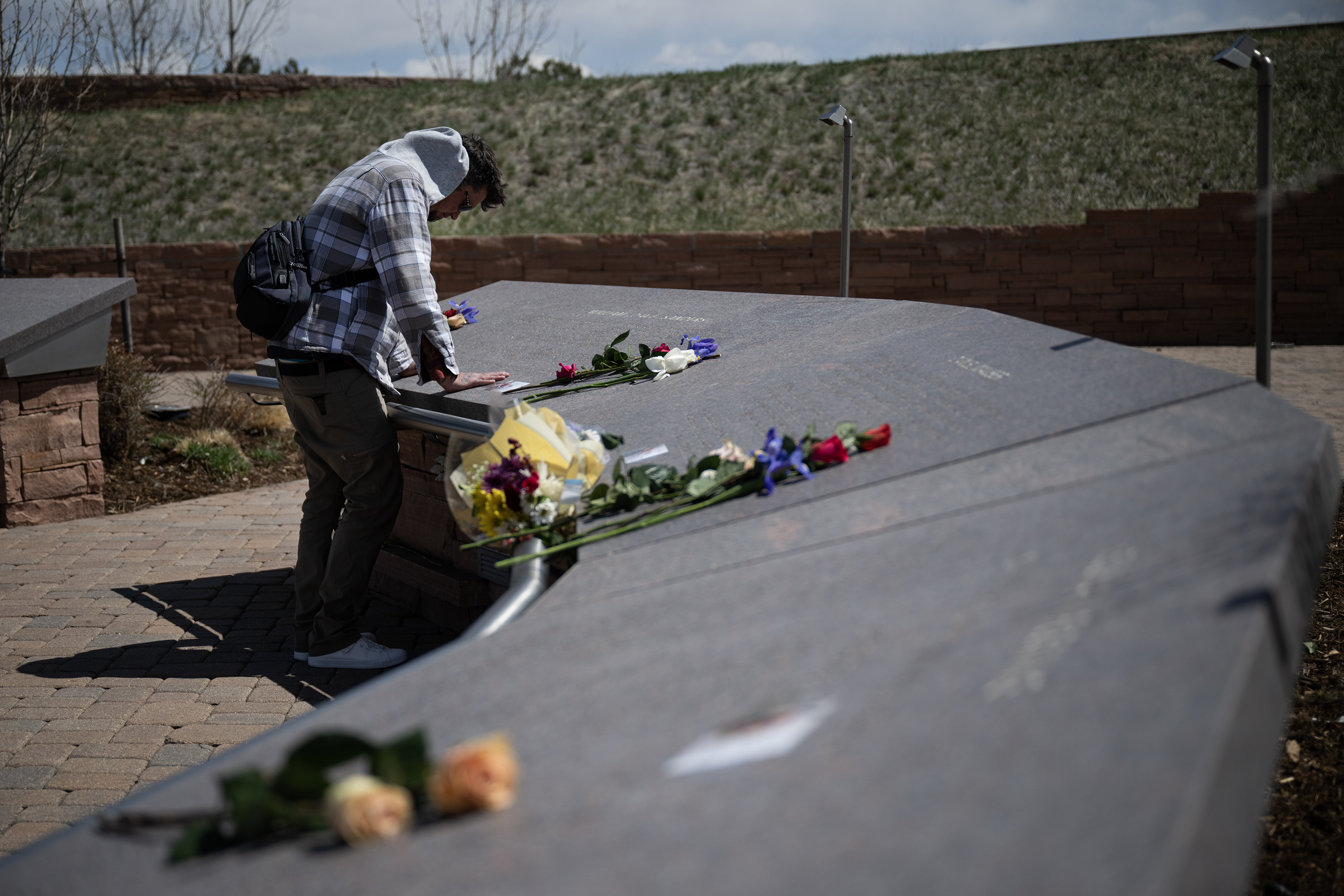 FILE PHOTO: Will Saggau, a 2001 graduate of Columbine High School who was present during the 1999 mass shooting, pauses and leans over the name of William David Sanders, the teacher killed that day, while visiting the Columbine Memorial on Thursday, April 20, 2023, in Robert F. Clement Park in Littleton, Colo. (Timothy Hurst/Denver Gazette) (TimHursttim.hurst@gazette.comhttps://secure.gravatar.com/avatar/aca82bd62b4ee425c598527cd6faa1b1?d=mm&r=g)