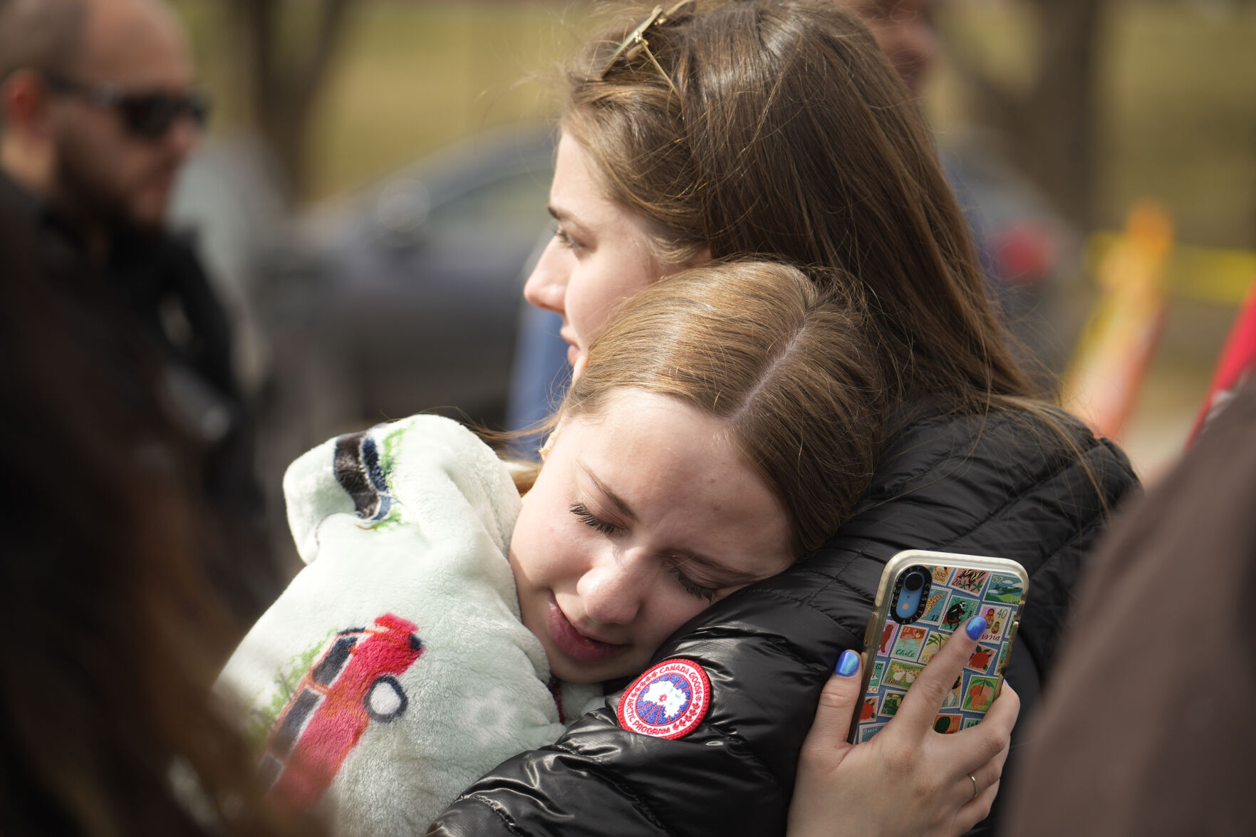 FILE PHOTO: Two women hug after a school shooting at East High School Wednesday, March 22, 2023, in Denver. Two school administrators were shot at the high school Wednesday morning after a handgun was found on a student subjected to daily searches, authorities said. (David Zalubowski/Associated Press)