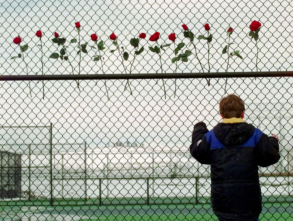 FILE PHOTO: A boy looks through the fence at the Columbine High School tennis courts in Littleton, Colo., Saturday, April 24, 1999. Thirteen roses were placed on the fence in remembrance of the 13 people killed by two gun wielding students at the school, Tuesday, April 20, 1999. (AP Photo/Eric Gay) (Eric Gay/Associate Press)
