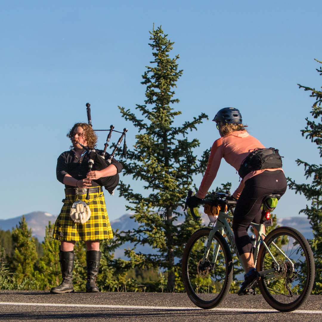 FILE PHOTO: A cyclist passes a man playing a bagpipes during a Triple Bypass cycling event. (Courtesy photo, Reid Neureiter/Triple Bypass)