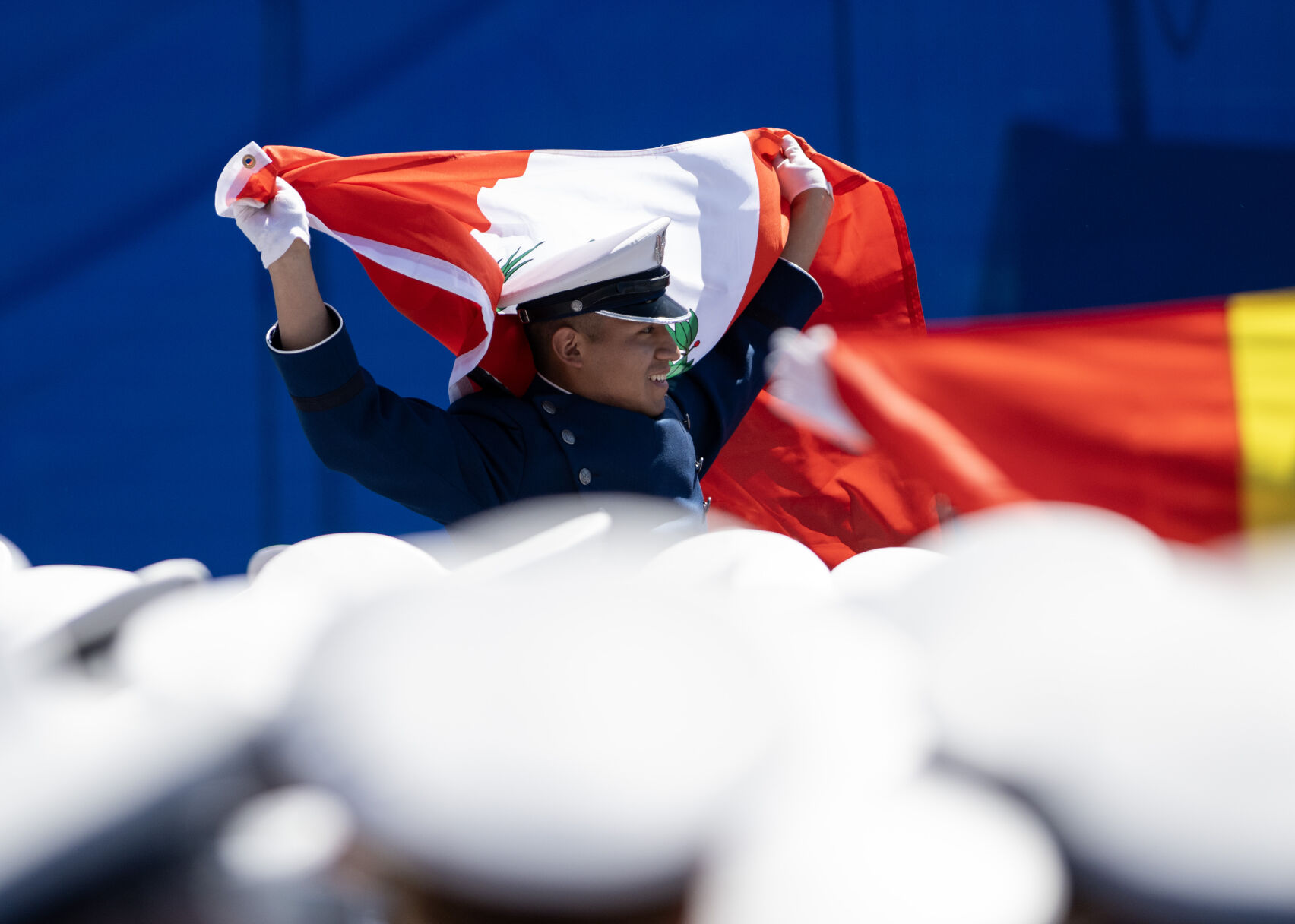 A graduate holds up a Peruvian flag during the United States Air Force Academy graduation at Falcon Stadium on Thursday, May 30, 2024, in Colorado Springs, Colo. (Parker Seibold, The Gazette) (Parker Seibold)