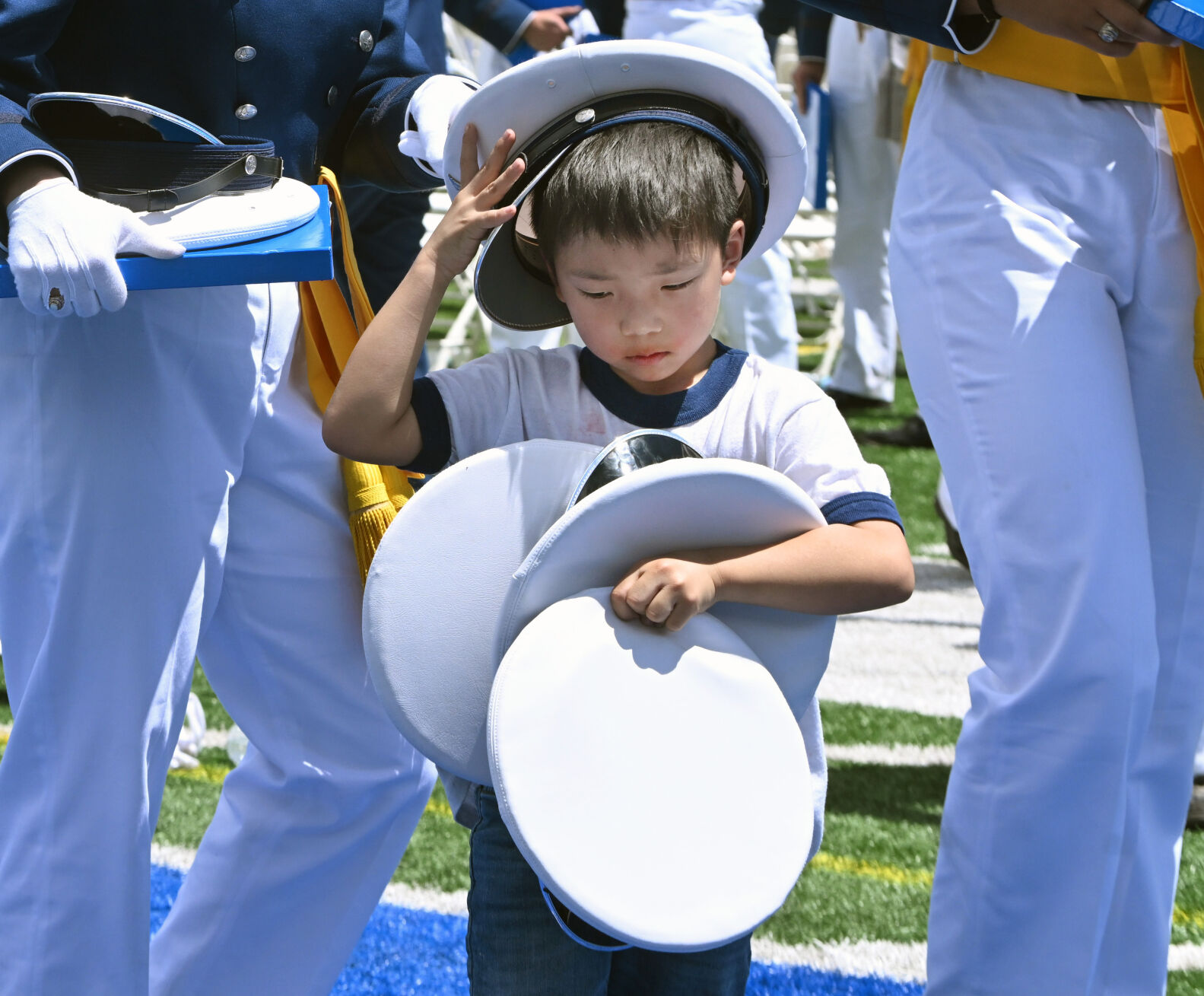 Six-year-old Jacob scored with an armful of hats after the Graduation Ceremony at Falcon Stadium at the Air Force Academy on Thursday, May 30, 2024. (Photo by Jerilee Bennett, The Gazette)
