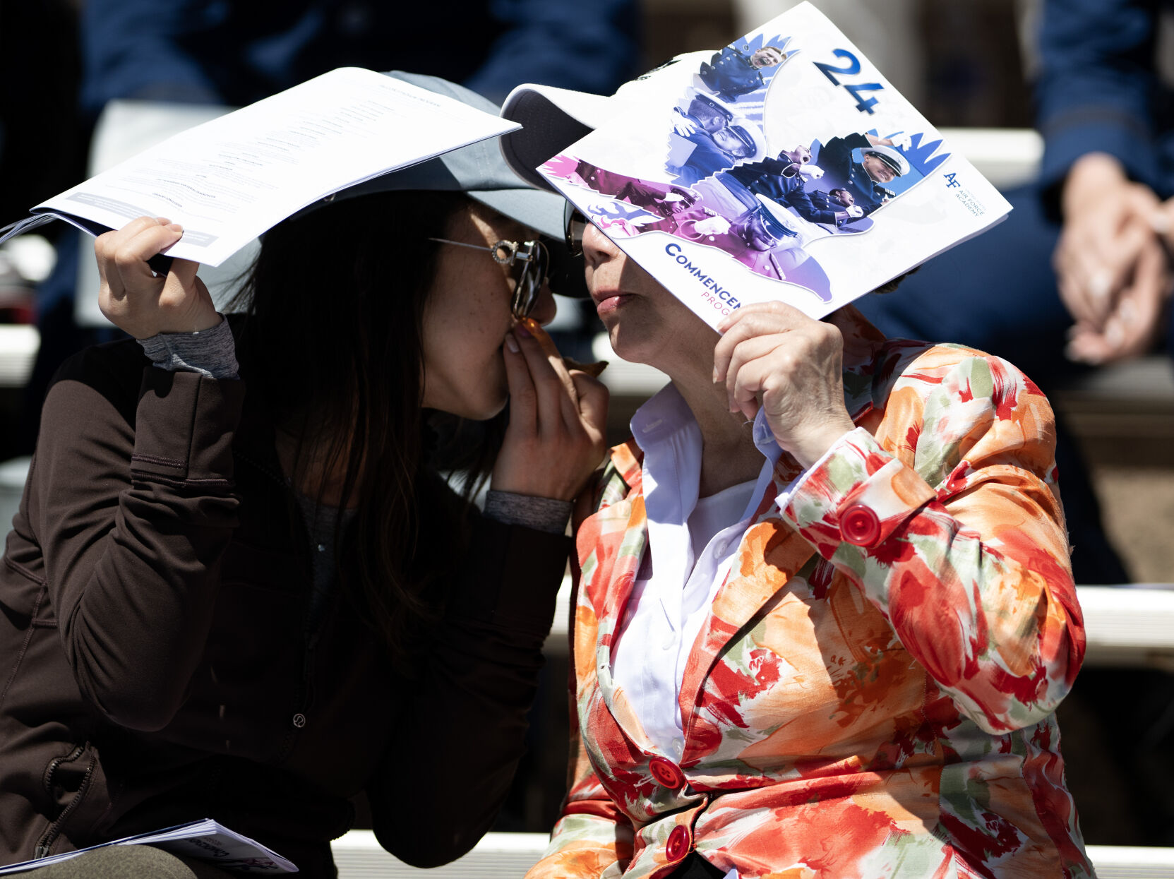 A women uses the United States Air Force Academy graduation program for shade at Falcon Stadium on Thursday, May 30, 2024, in Colorado Springs, Colo. (Parker Seibold, The Gazette) (Parker Seibold)