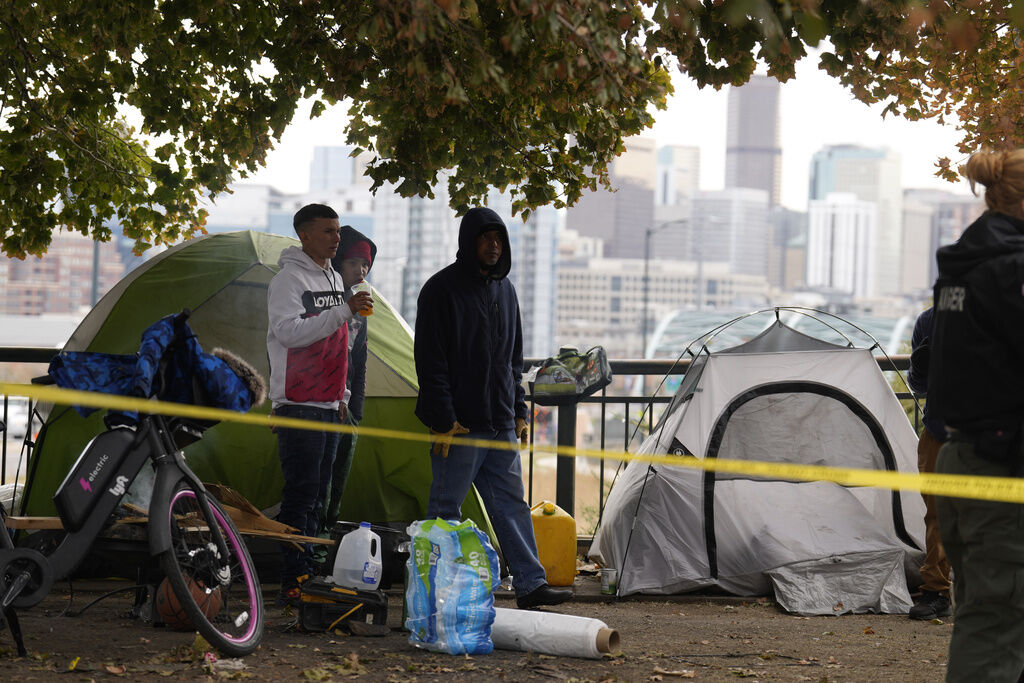 Occupants look on during a city-sponsored sweep of an encampment overlooking the city skyline on Diamond Hill Wednesday, Nov. 1, 2023, in Denver. The sweep was just one of several staged in various locations across the Mile High City. (AP Photo/David Zalubowski) (David Zalubowski)