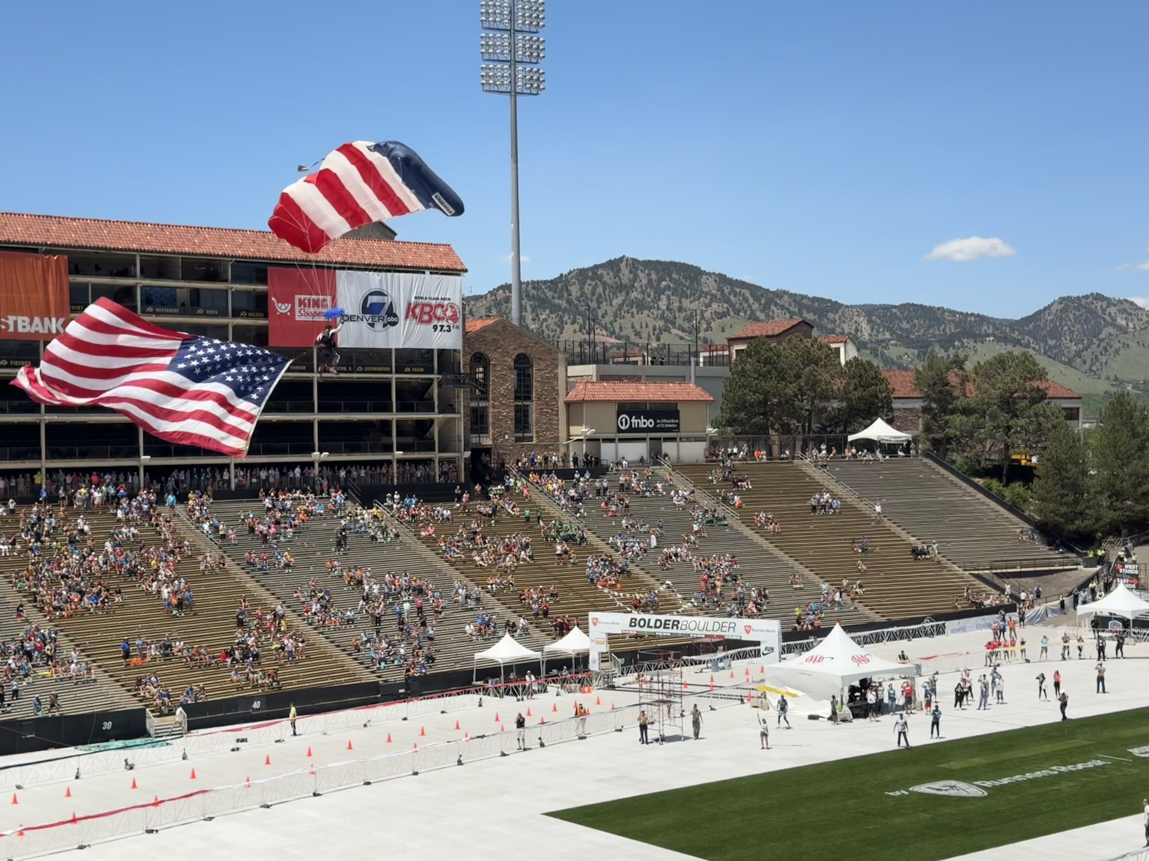 An American flag and paratrooper land at Folsom Field in on the University of Colorado Boulder campus as part of the 44th BOLDERBoulder on Monday, May 27, 2024. (StephenBarrstephen.barr@gazette.comhttps://secure.gravatar.com/avatar/040b744c16d39530207b3e35b456105e?d=mm&r=g)