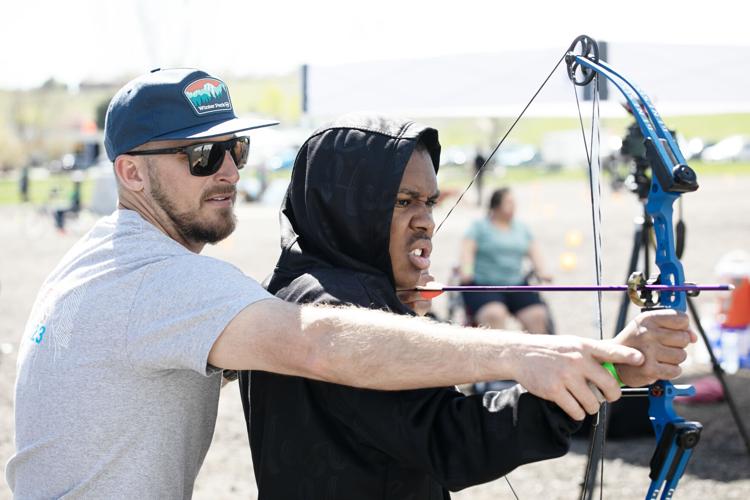 Michael Riley, a volunteer coordinator with National Sports Center for the Disabled (NCSD), helps Simeon Jackson
