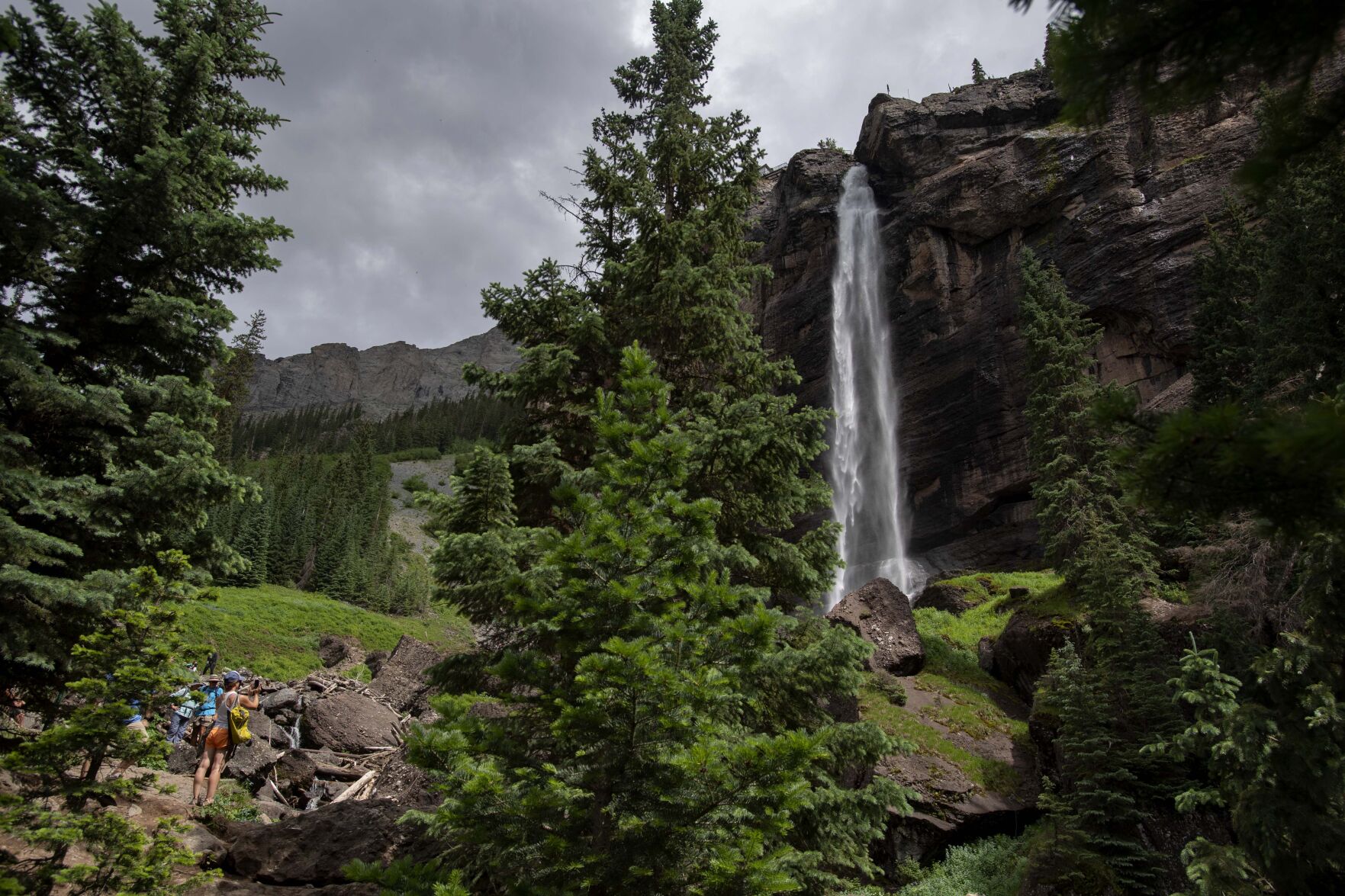Hikers stand below the 365-foot Bridal Veil Falls outside Telluride, Colo., Saturday, July 17, 2021. The falls can be reached by hiking a rugged 1.1 mile trail or by a 1.5 mile 4x4 road. (The Gazette, Christian Murdock) (Christian Murdock/The Gazette)