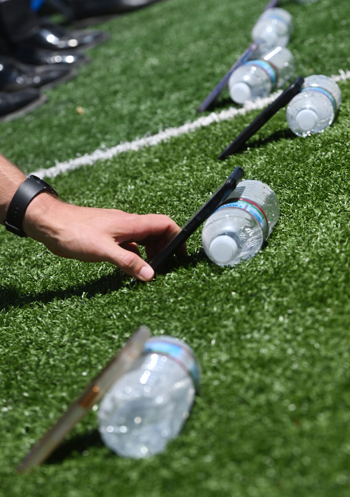 Cadets rest their cell phones on water bottles to do selfies during the hat toss and Thunderbird flyover at the Graduation Ceremony at Falcon Stadium at the Air Force Academy on Thursday, May 30, 2024. (Photo by Jerilee Bennett, The Gazette)