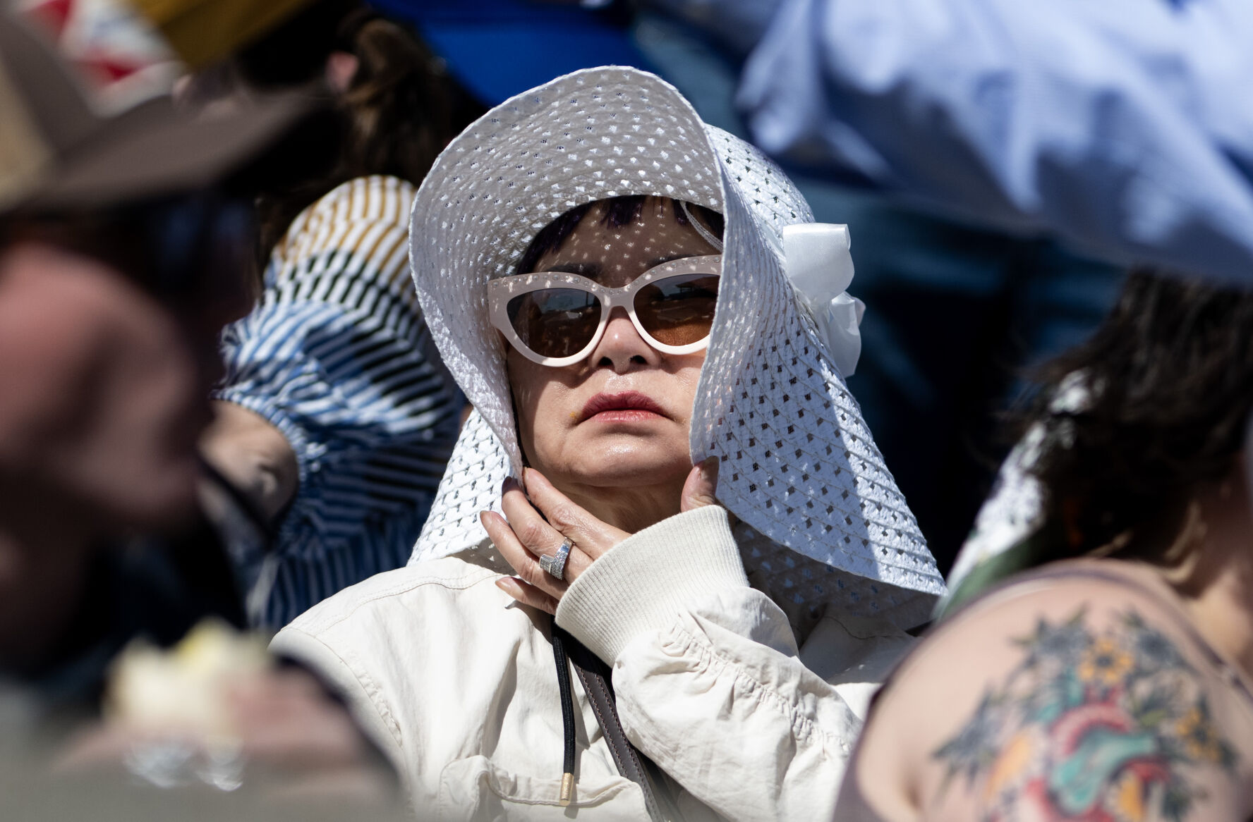 An attendee pulls her hat closed to get some shade during the United States Air Force Academy graduation at Falcon Stadium on Thursday, May 30, 2024, in Colorado Springs, Colo. (Parker Seibold, The Gazette) (Parker Seibold)