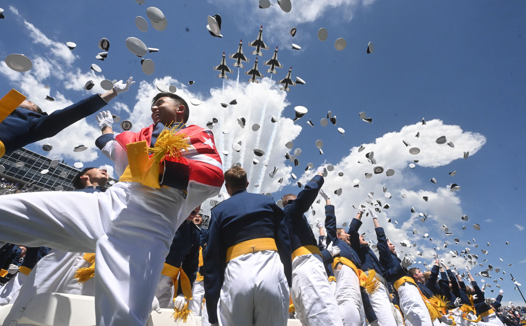 Cadet Jonathan Loh from Singapore, left, and the class of 2024 at the United States Air Force Academy toss their hats in the air as the Thunderbirds fly over Falcon Stadium on Thursday, May 30, 2024, at the conclusion of the commencement ceremony in Colorado Springs, Colo. (Jerilee Bennett, The Gazette)