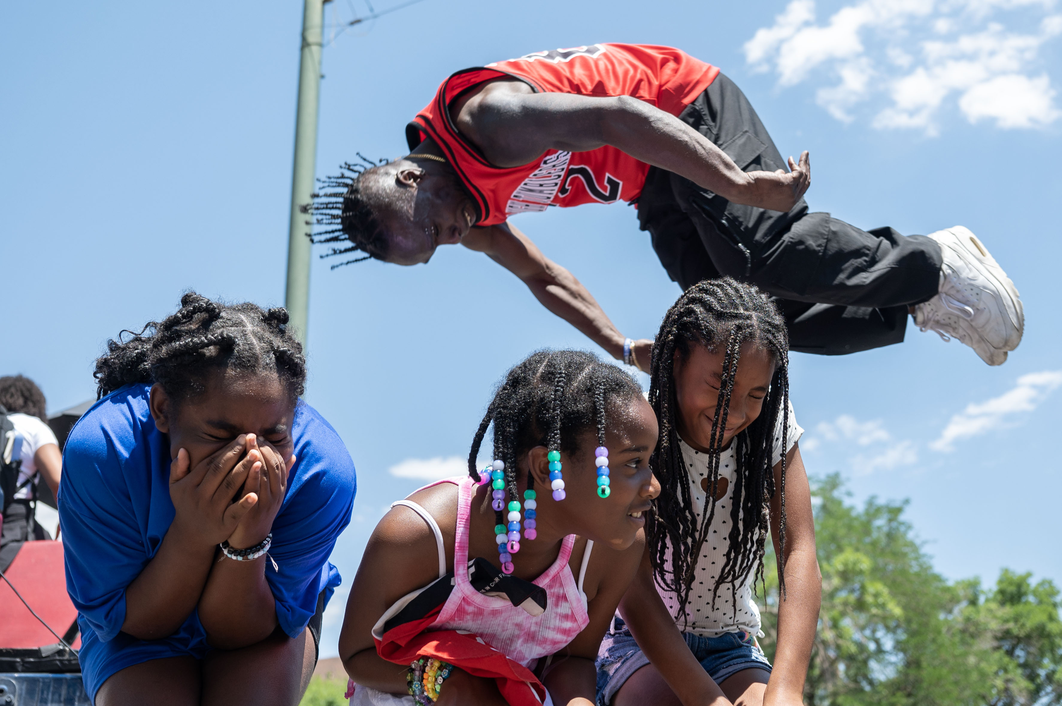 Kids reacts as Coach Ozell Williams, form Mile High Tumblers 5280, jumps over the three of the them during the Juneteenth parade in Denver on Saturday, June 15, 2024. (Stephen Swofford, Denver Gazette) (Stephen Swofford The Gazette)
