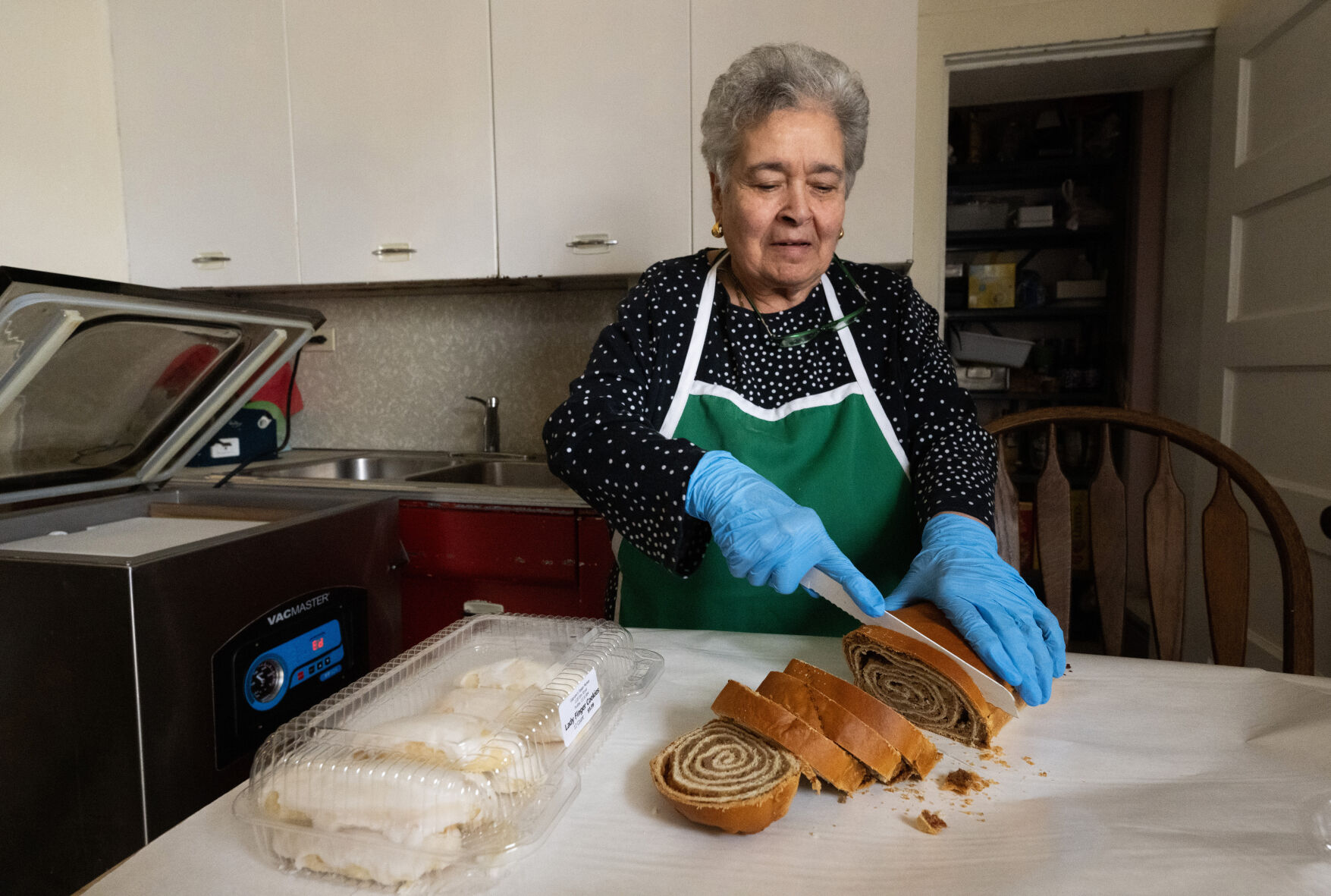 Grandma Josephine Gagliano slices the walnut potica bread with raisins in the backroom at Gagliano’s Italian Market & Deli in Pueblo. On the left are the fresh Ladyfinger cookies the family make at the market. (Christian Murdock, The Gazette)