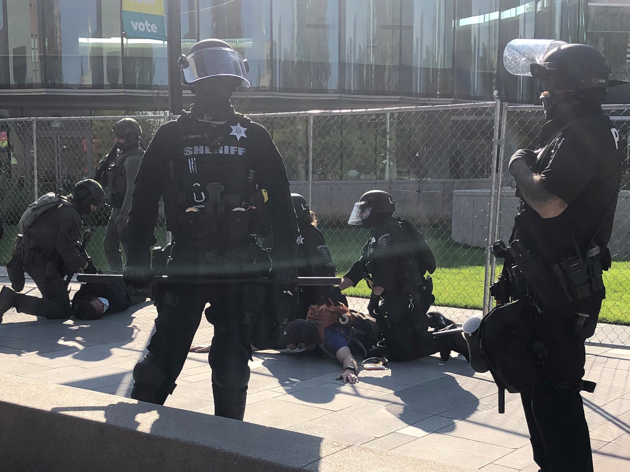 Police tackle Matthew Dolloff and a 9News producer following a fatal shooting in Civic Center Park on Oct. 10, 2020. ((Photo by Julia Cardi, The Denver Gazette))