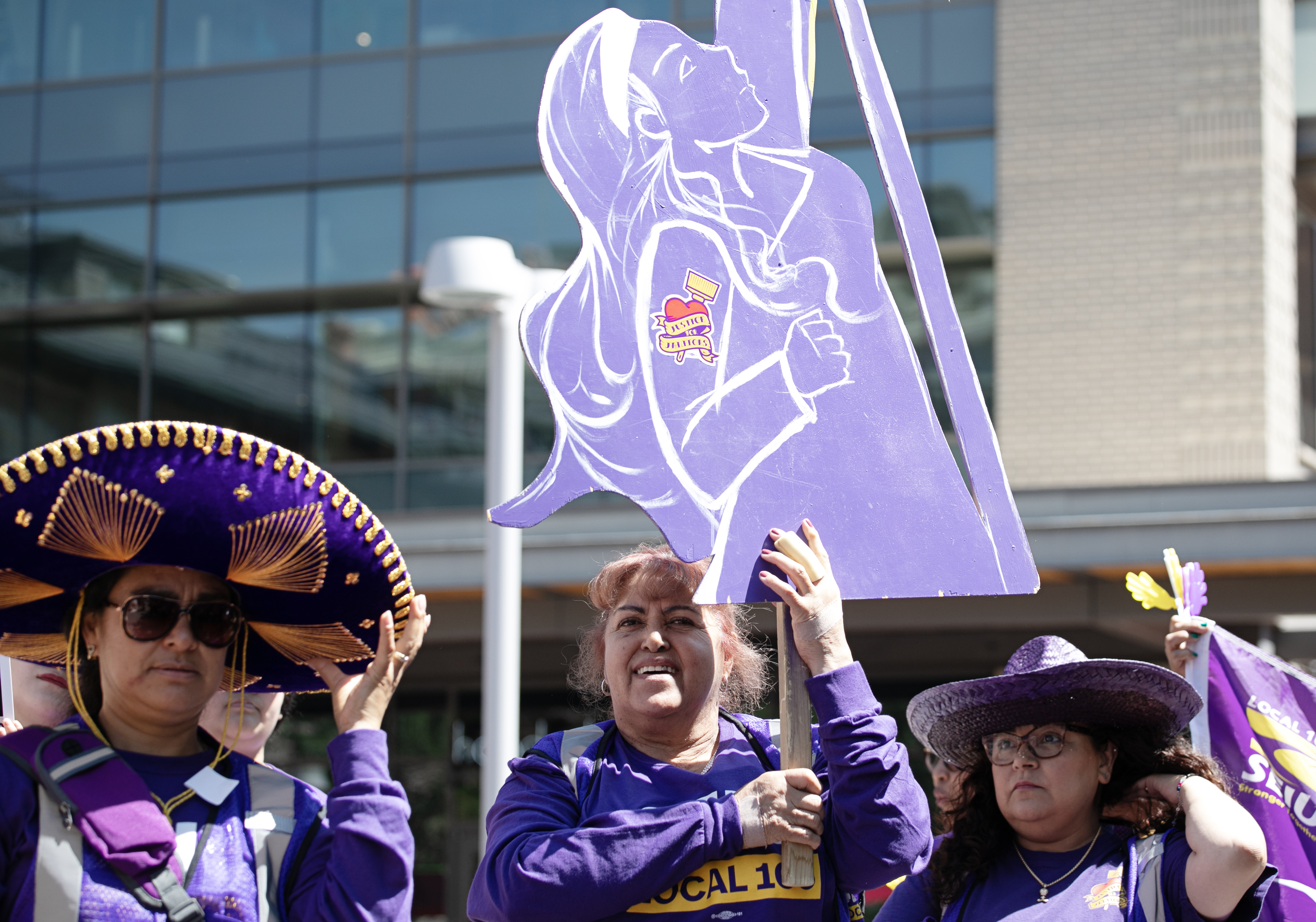 Maria Hernandez, center, holds up a cleaning lady sign, with other members of the Service Employees International Union (SEIU) Local 105 at a 