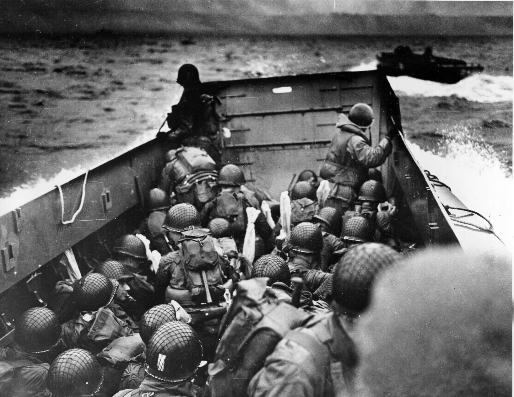 FILE — In this photo provided by the U.S. Coast Guard, a U.S. Coast Guard landing barge, tightly packed with helmeted soldiers, approaches the shore at Normandy, France, during initial Allied landing operations, June 6, 1944. The D-Day invasion that helped change the course of World War II was unprecedented in scale and audacity. Veterans and world dignitaries are commemorating the 79th anniversary of the operation. (U.S. Coast Guard via AP, File) (Uncredited)