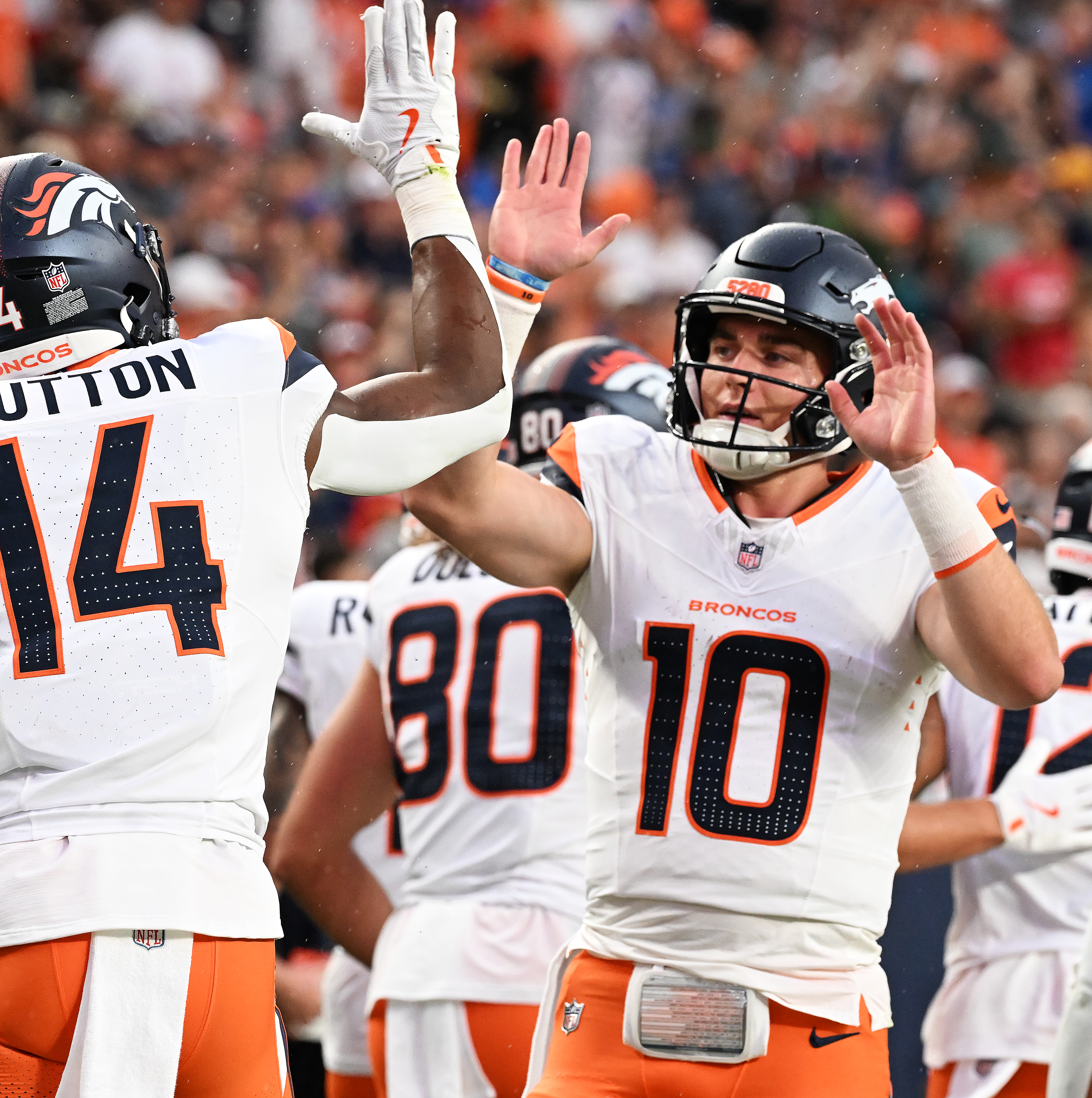 Broncos quarterback Bo Nix gets a high five from wide receiver Courtland Sutton after Nix threw for his first touchdown at Empower Field at Mile High during the second quarter of a preseason game against the Packers on Sunday, Aug. 18, 2024. (Jerilee Bennett The Gazette)