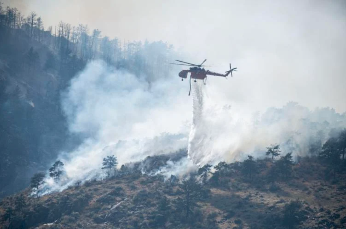 A helicopter drops water on the Alexander Mountain Fire. Photo Stephen Swofford, Denver Gazette.