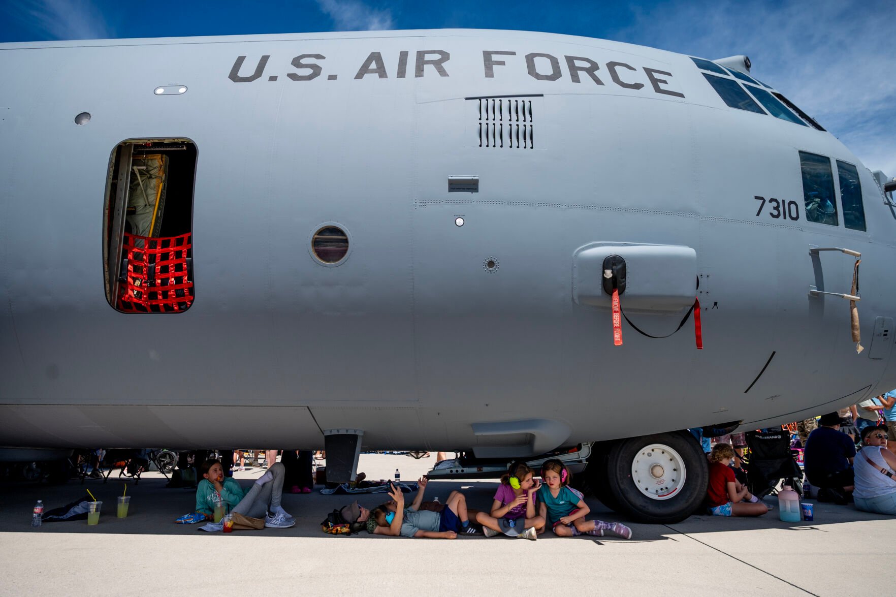 People sit in the shade of a C-130 Hercules as temperatures reach the high-90s at the Pikes Peak Regional Airshow at the Colorado Springs Airport on Saturday, Aug. 17, 2024. (Parker Seibold, The Gazette) (Parker Seibold The Gazette)
