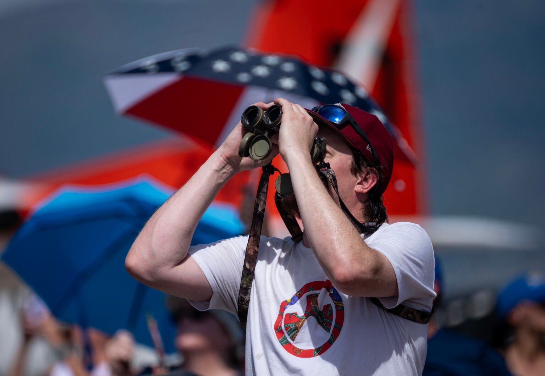 A spectator uses binoculars to watch the Pikes Peak Regional Airshow at the Colorado Springs Airport on Saturday, Aug. 17, 2024. (Parker Seibold, The Gazette) (Parker Seibold The Gazette)