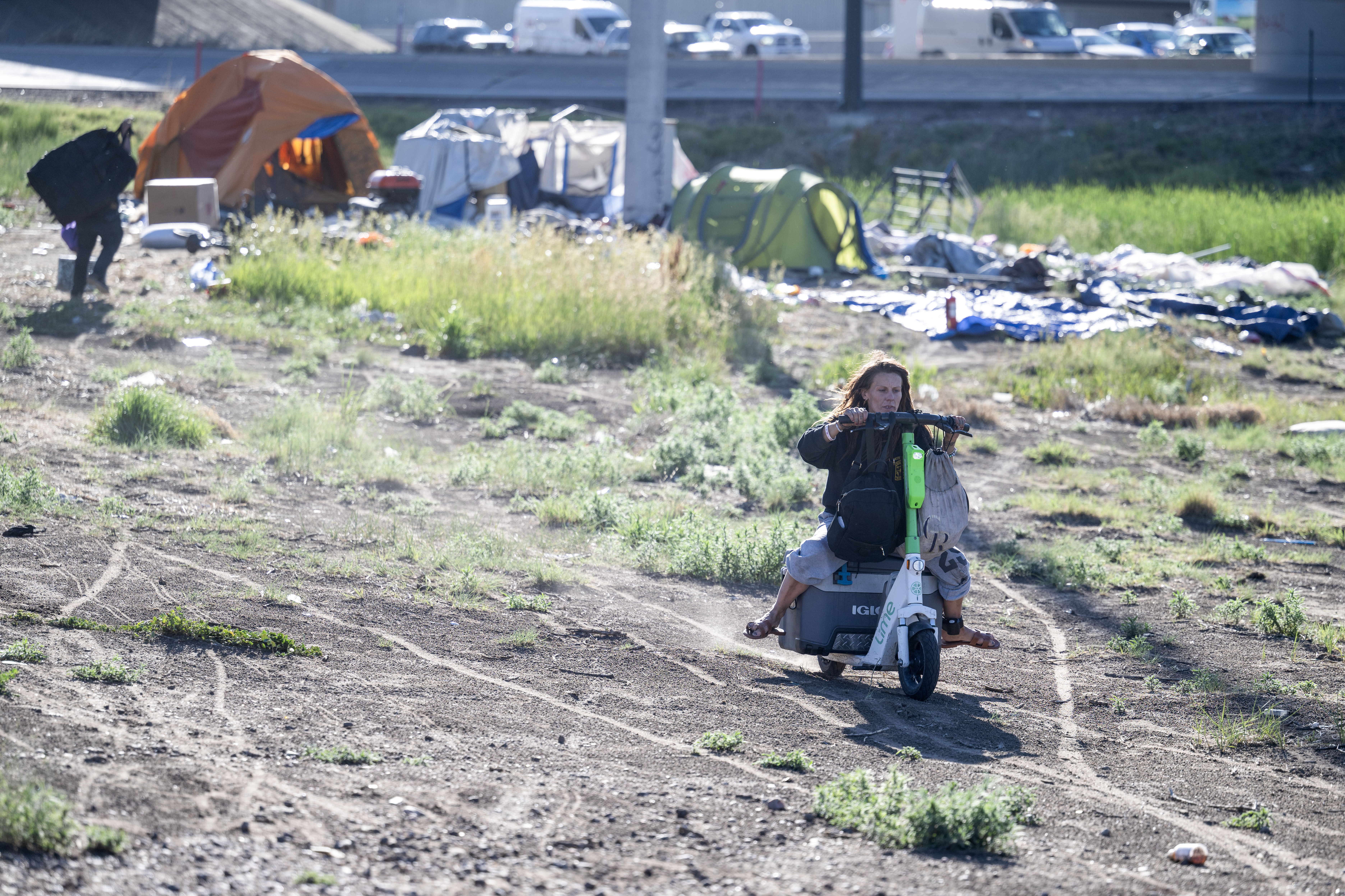 Casey Horn rides a scooter away from her encampment as she and the other occupants rush to clear the area before a police sweep near 38th and Fox in Denver on Thursday, June 13, 2024. (StephenSwoffordPhotographerstephen.swofford@gazette.comhttps://secure.gravatar.com/avatar/1ddcaf11c5d70eaa58546ddc4e038687?d=mm&r=g)