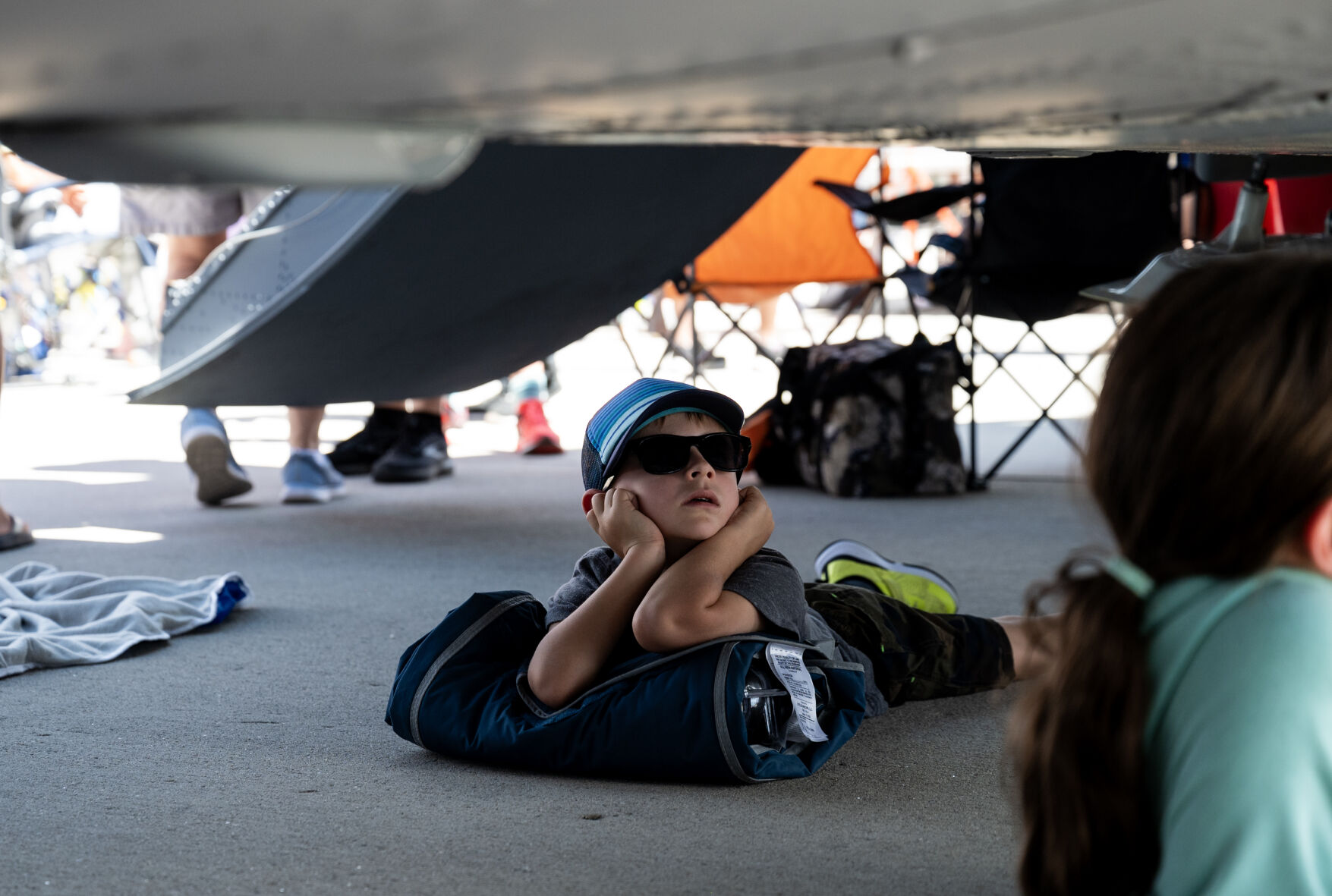 A young spectator plugs his ears and takes shelter under a C-130 Hercules on display at the Pikes Peak Regional Airshow at the Colorado Springs Airport on Saturday, Aug. 17, 2024. (Parker Seibold, The Gazette) (Parker Seibold The Gazette)