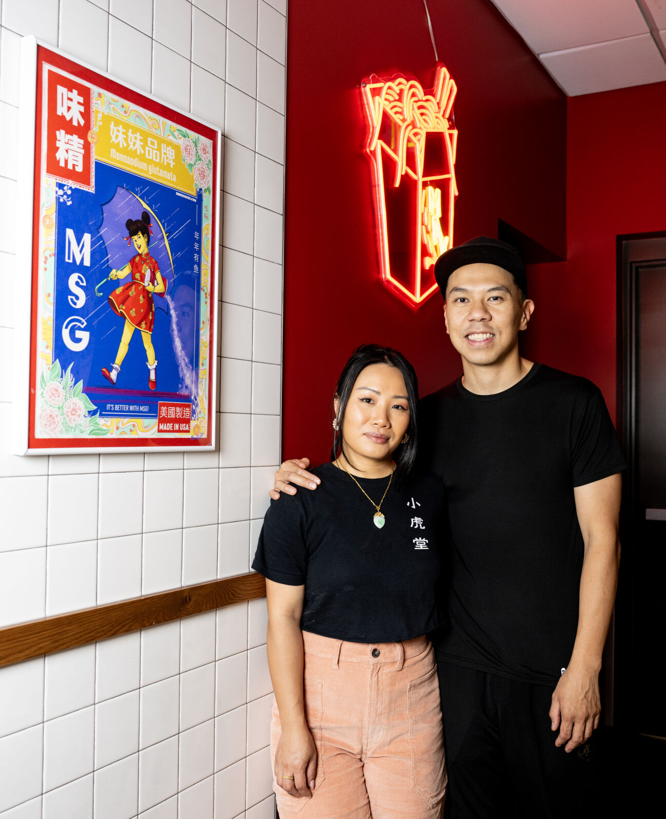 Doris Yuen, left, and chef Kenneth Wan, owners of MAKfam, pose for a portrait next to Brenda Chi’s “MSG Girl” poster inside the Denver restaurant on Monday, Aug. 5, 2024. (Parker Seibold, The Gazette)w (Parker Seibold, The Gazette)