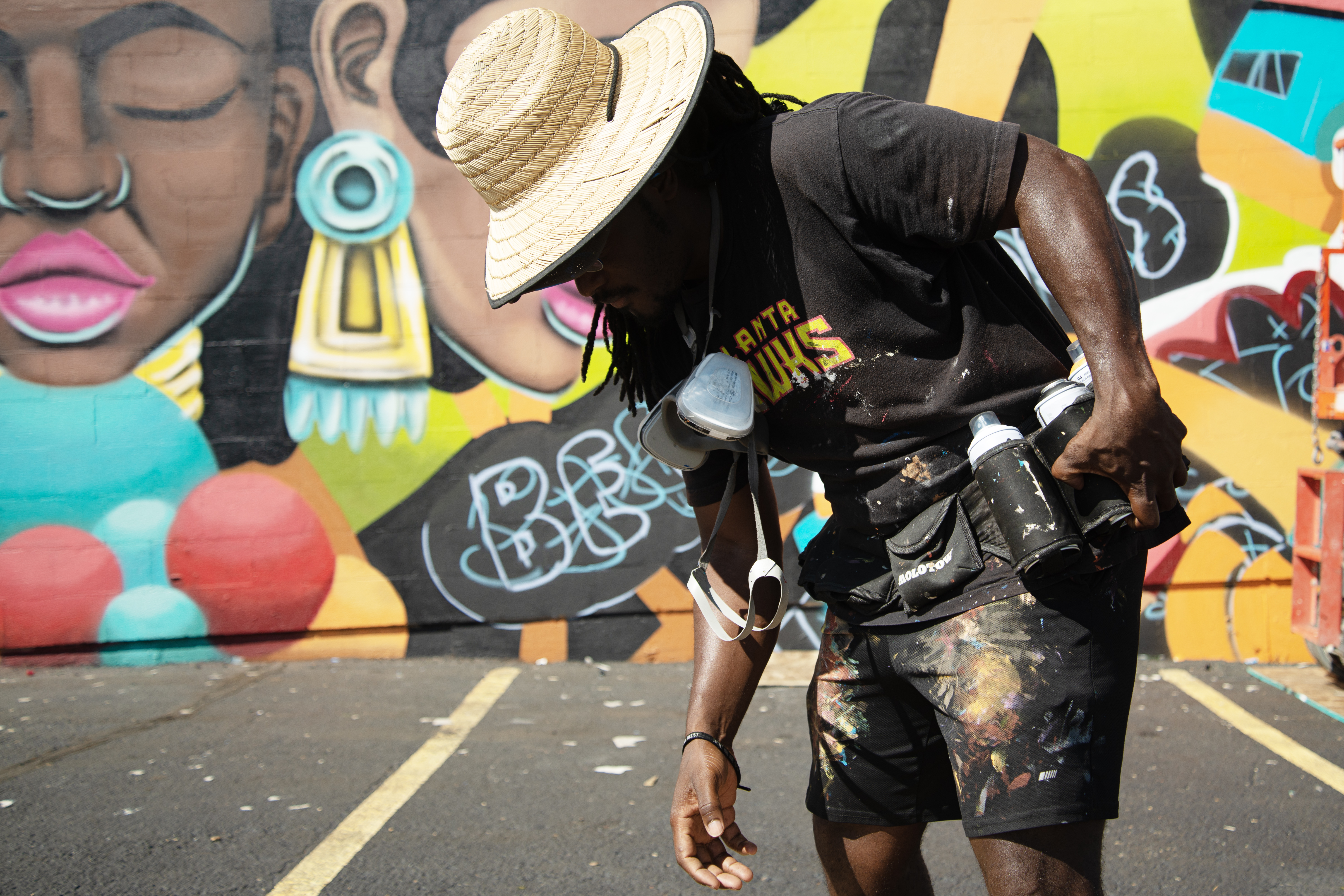 George F. Baker III loads spray paint canisters into a work belt while working on his piece, 