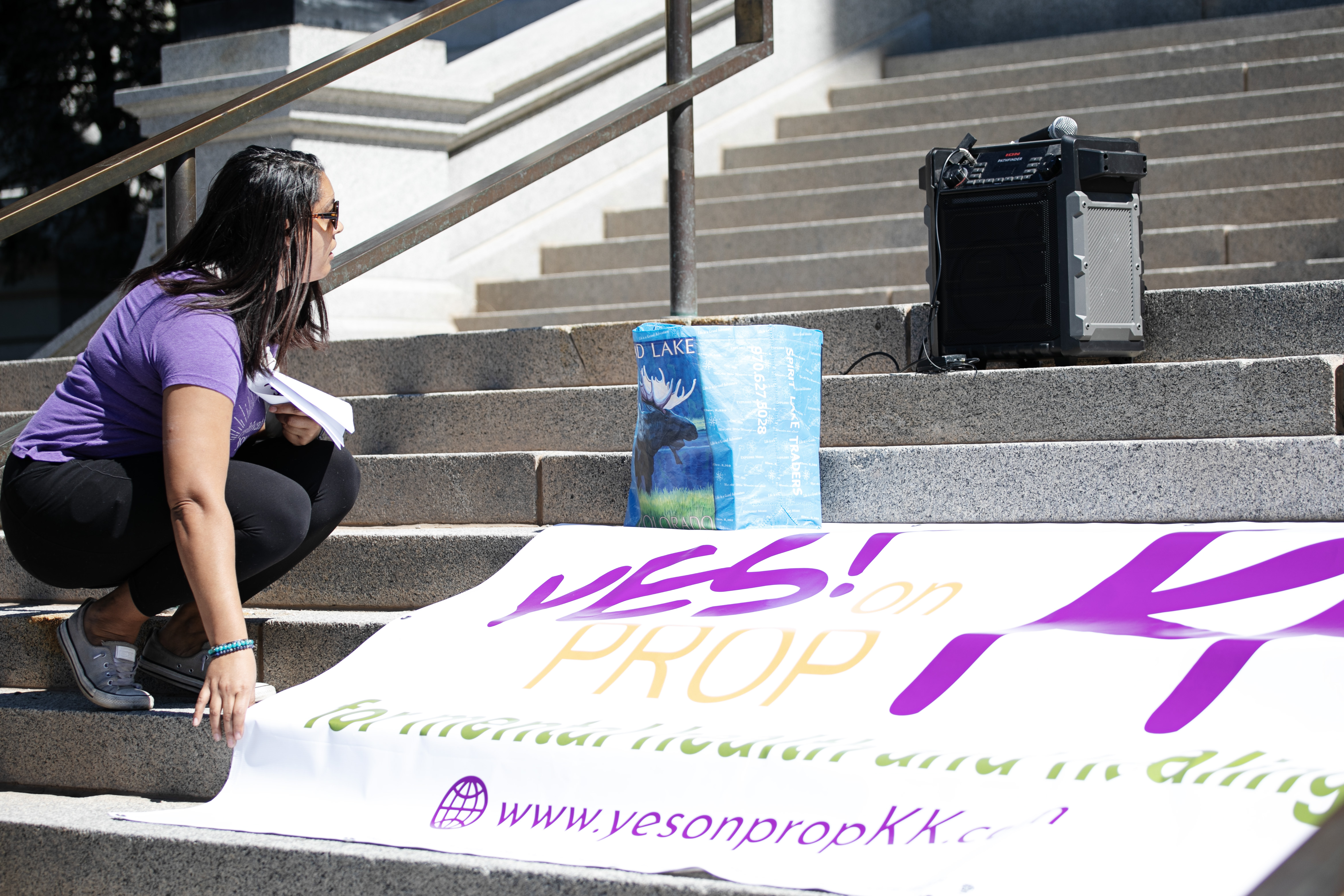 Eunice Brownlee helps unfurl a sign promoting Prop KK, a ballot initiative proposing a 6.5 percent tax increase on guns and ammunition in Colorado, on the state capitol building's steps in Denver on Thursday, Sept. 12, 2024. 