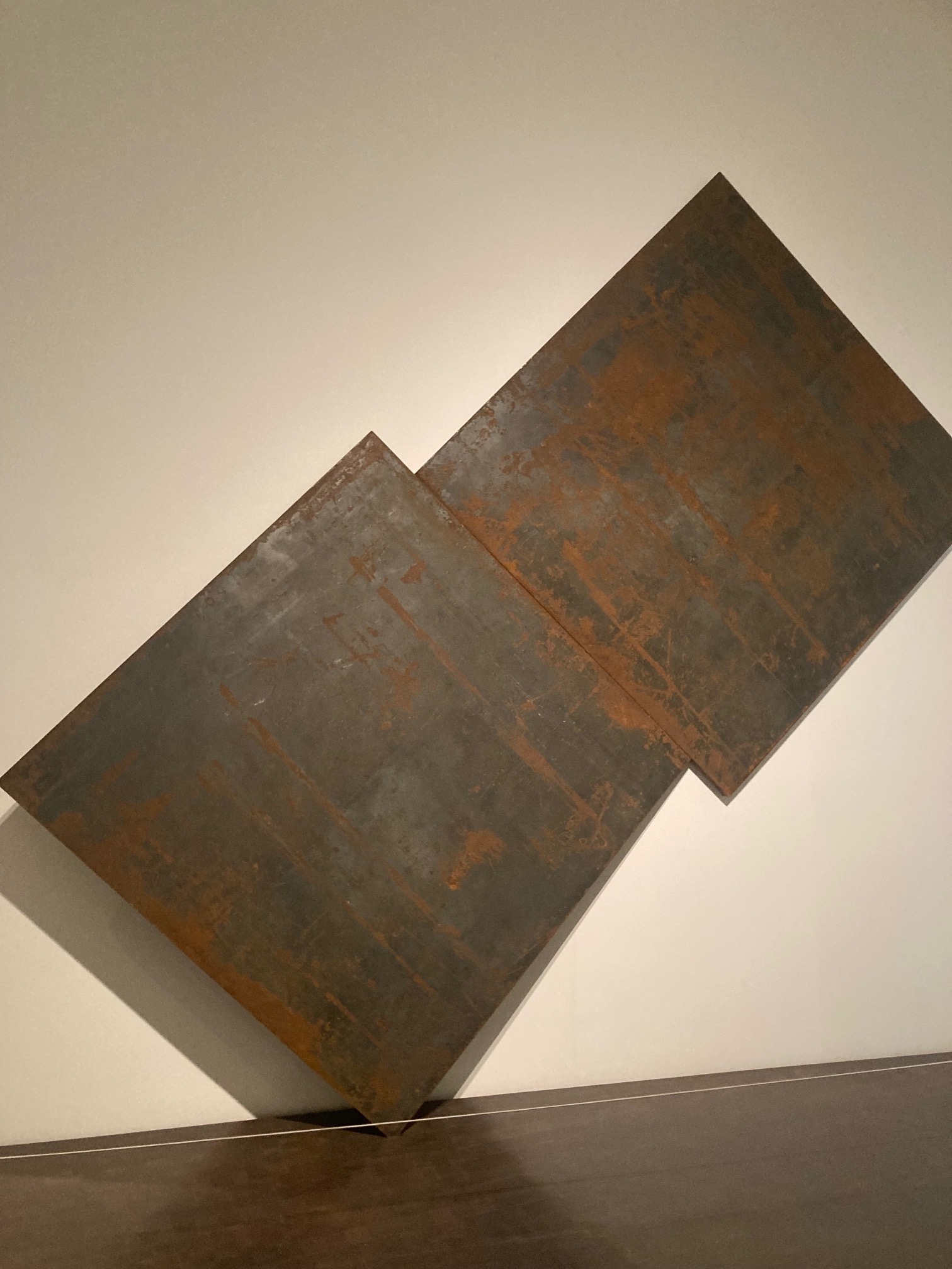 Denver Art Museum Curator Rory Padeken had a wall taken down to unveil “Basic Maintenance,” a sculpture by Richard Serra, one of the great minimalist sculptors of the 20th century, who died in 2024. “I am glad the sculpture was set free [from the wall]. The sculpture lives here permanently installed in this position because it weighs over 6,000 pounds, so the building itself was reinforced at the point in which the sculpture stands on to carry its weight,” Padeken said. “This sculpture is held up through sheer physics. It’s two steel plates balanced in such a way that it holds itself. It’s two points and the force of gravity keeping it in place.” (Colleen Smith/Special to The Denver Gazette)