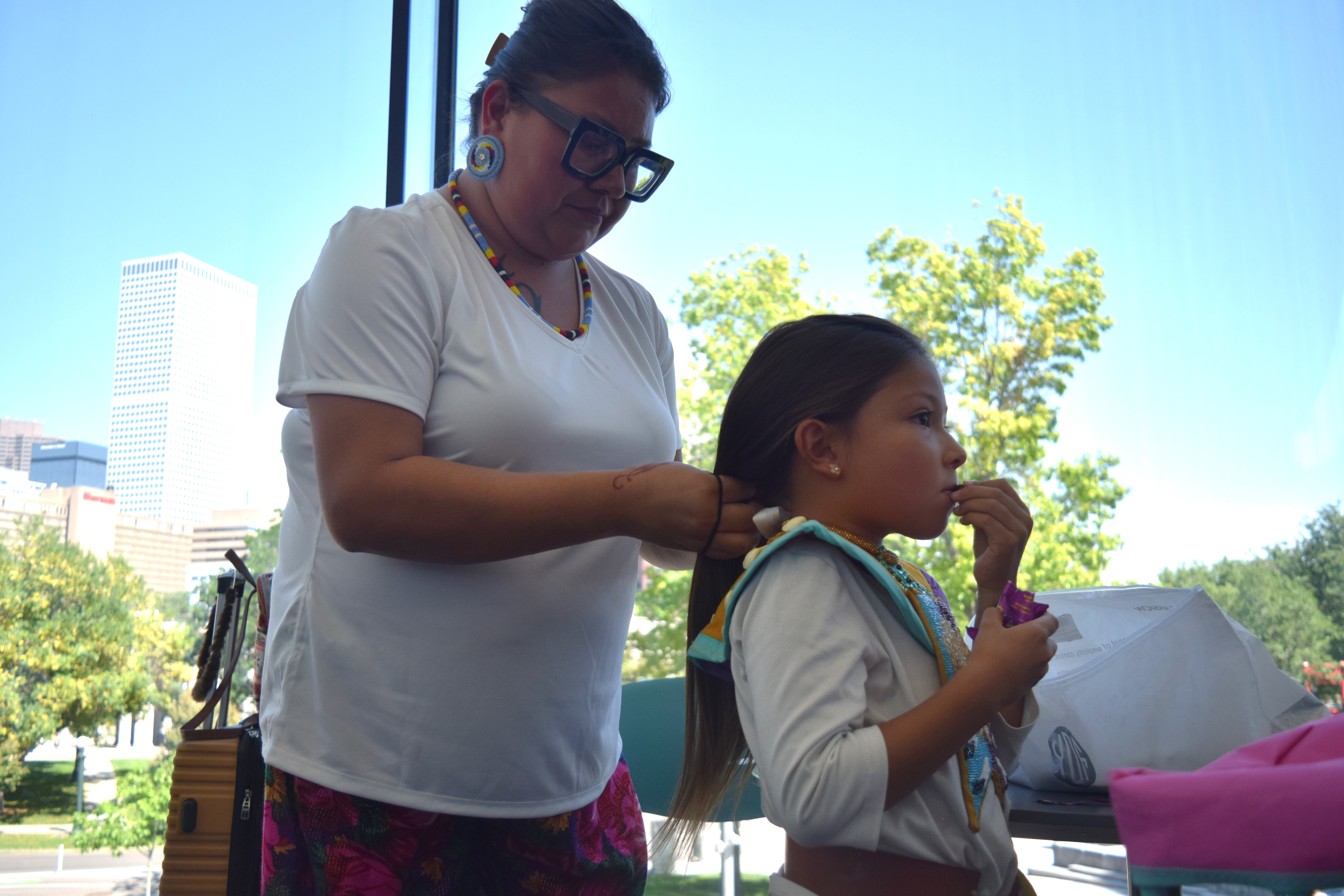 Sierrah Wilson braids her niece, six-year-old Mariah Wightman's, hair prior to the Tiny Tots dance competition at the Friendship Powwow on Saturday.