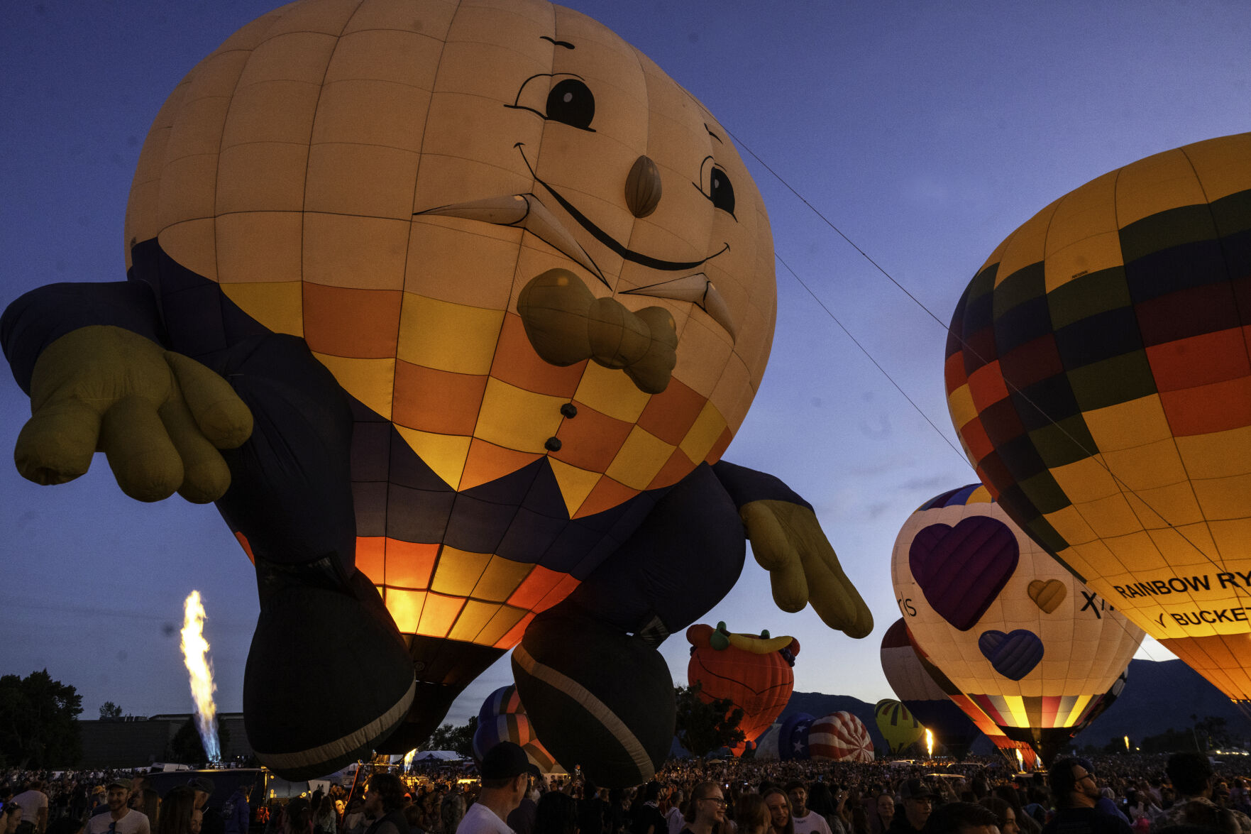 The Humpty Dumpty balloon looks down over a massive crowd during a balloon glow evening of the Colorado Springs Labor Day Lift Off on Sunday, Sept. 1, 2024.