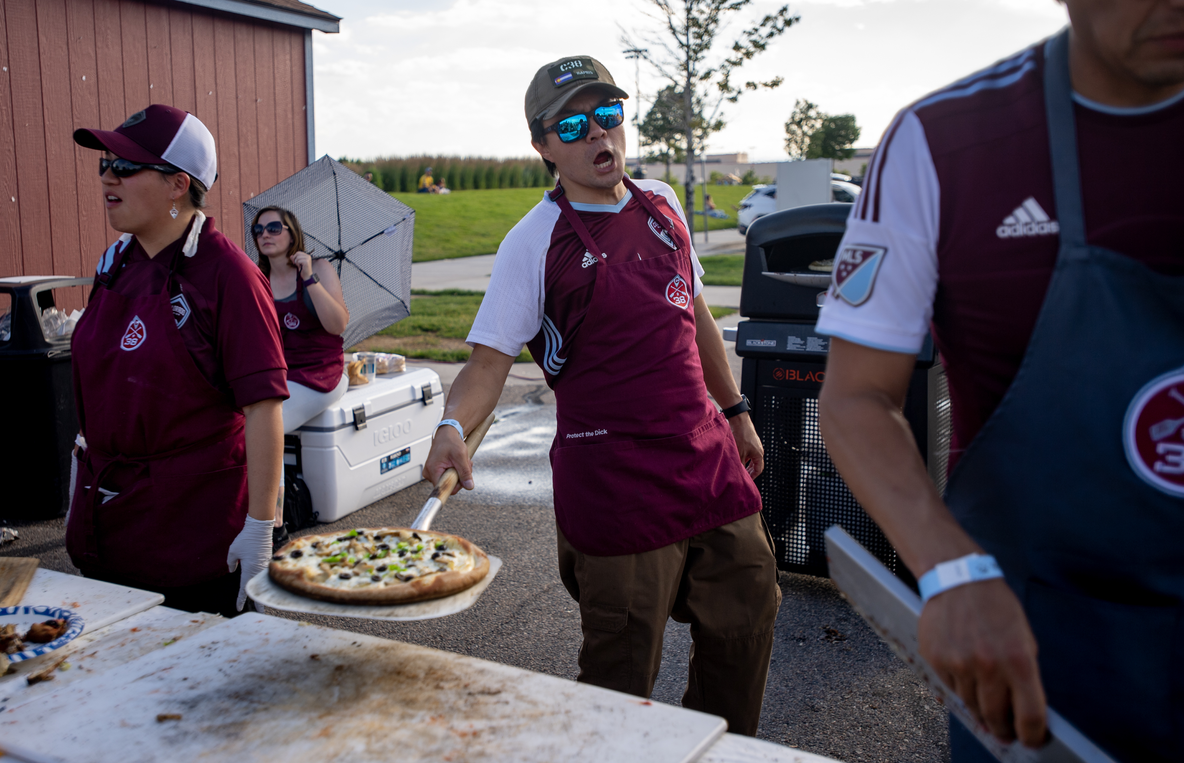 David Hang serves wood fired pizzas at the Centennial 38 tailgate outside Dick’s Sporting Goods Park before a Rapids game on Saturday, July 8, 2023. What began 10 years ago as a keg and some hot dogs among friends in Centennial 38 has grown into six taps, wood-fired pizza, live music and countless folks on a giddy Saturday nights.(Parker Seibold, The Gazette) (Parker Seibold)