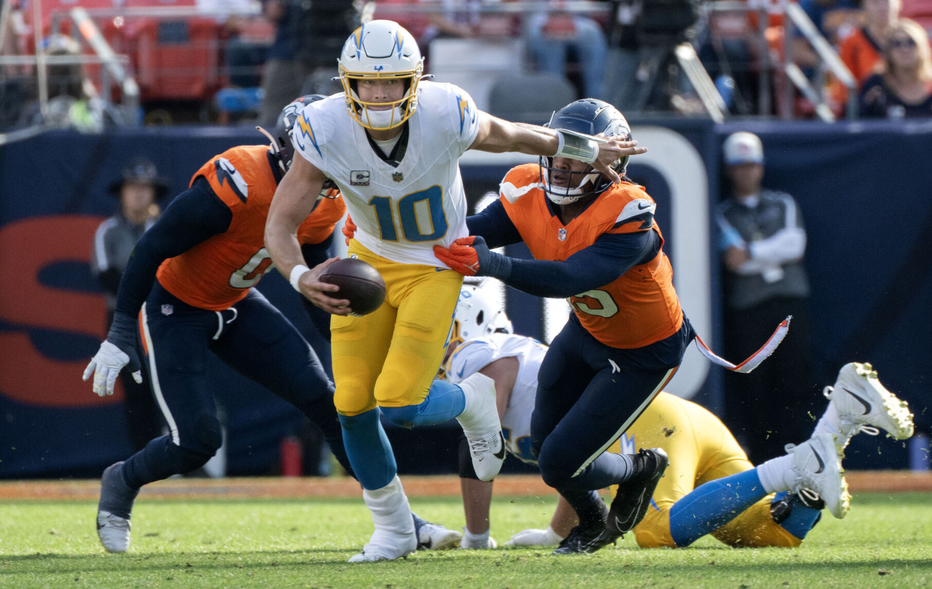 Los Angeles Chargers quarterback Justin Herbert (10) runs past Denver Broncos linebackers Nik Bonitto (15) and Jonathon Cooper (0) during the second half Sunday, Oct. 14, 2024, at Empower Field at Mile High in Denver. (The Gazette, Christian Murdock) (Christian Murdock)