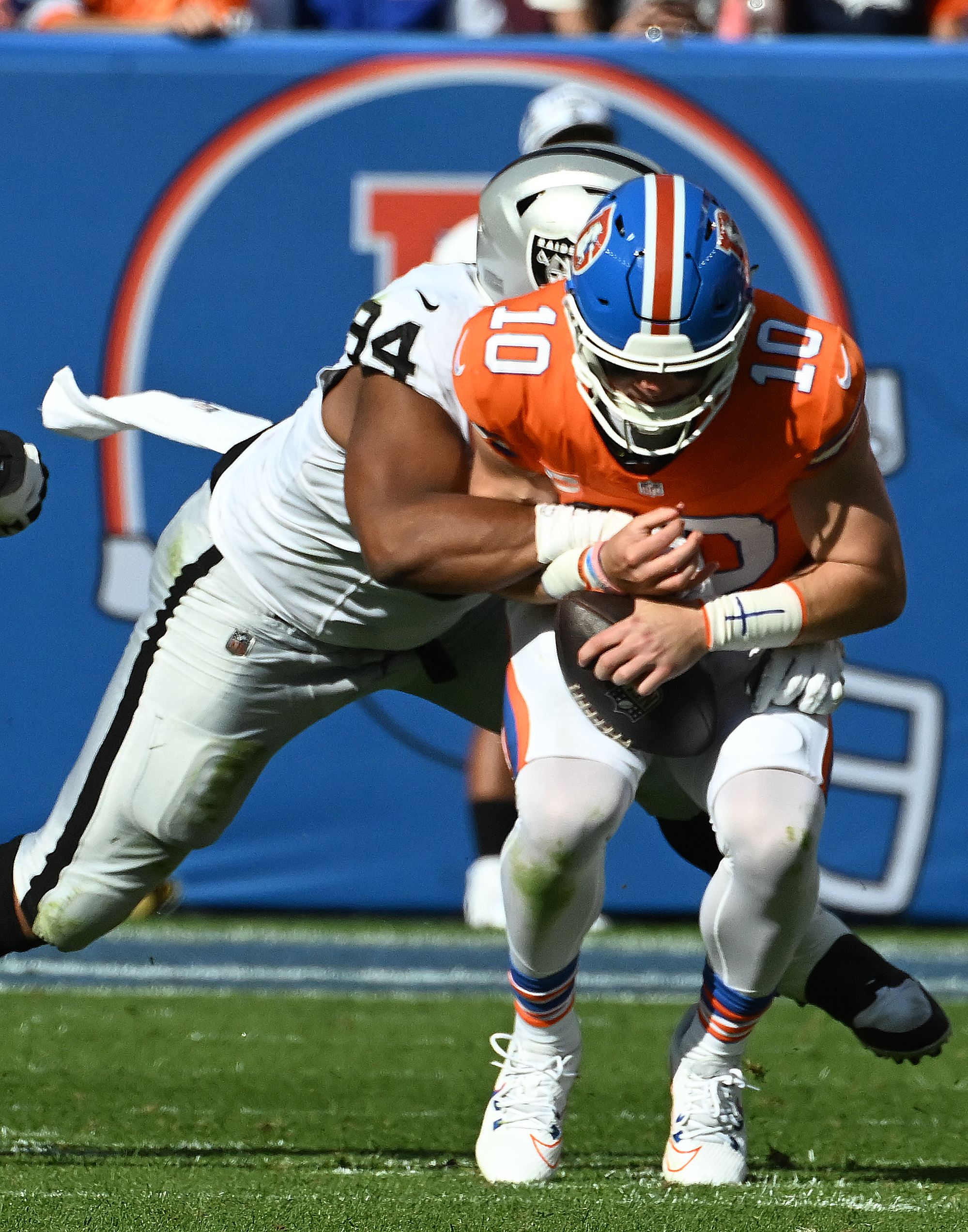 Denver Broncos quarterback Bo Nix (10) is sacked by Las Vegas Raiders safety Thomas Harper (34) during a game against the Raiders at Empower Field at Mile High on Sunday, Oct. 6, 2024.