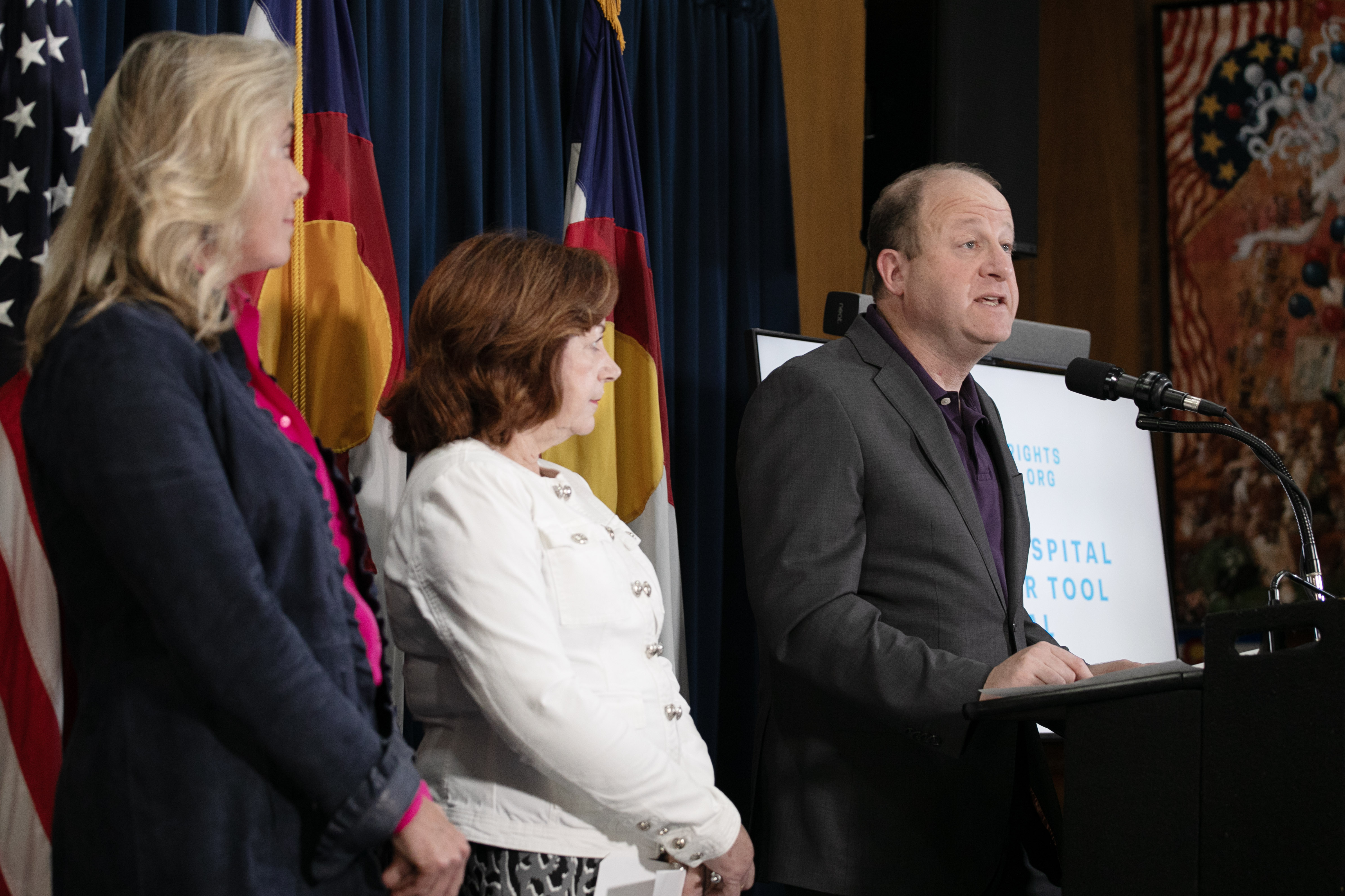 From left, Cynthia Fisher, founder of Patient Rights Advocate, Lt. Gov. Dianne Primavera and Gov. Jared Polis address members of the media about the launch of a new online database for Colorado healthcare patients to compare costs from various providers in the state created by the non-profit, Patient Rights Advocate, from the Colorado State Capitol on Tuesday, Oct. 22, 2024. Costs of procedures and treatment can vary as much as, 