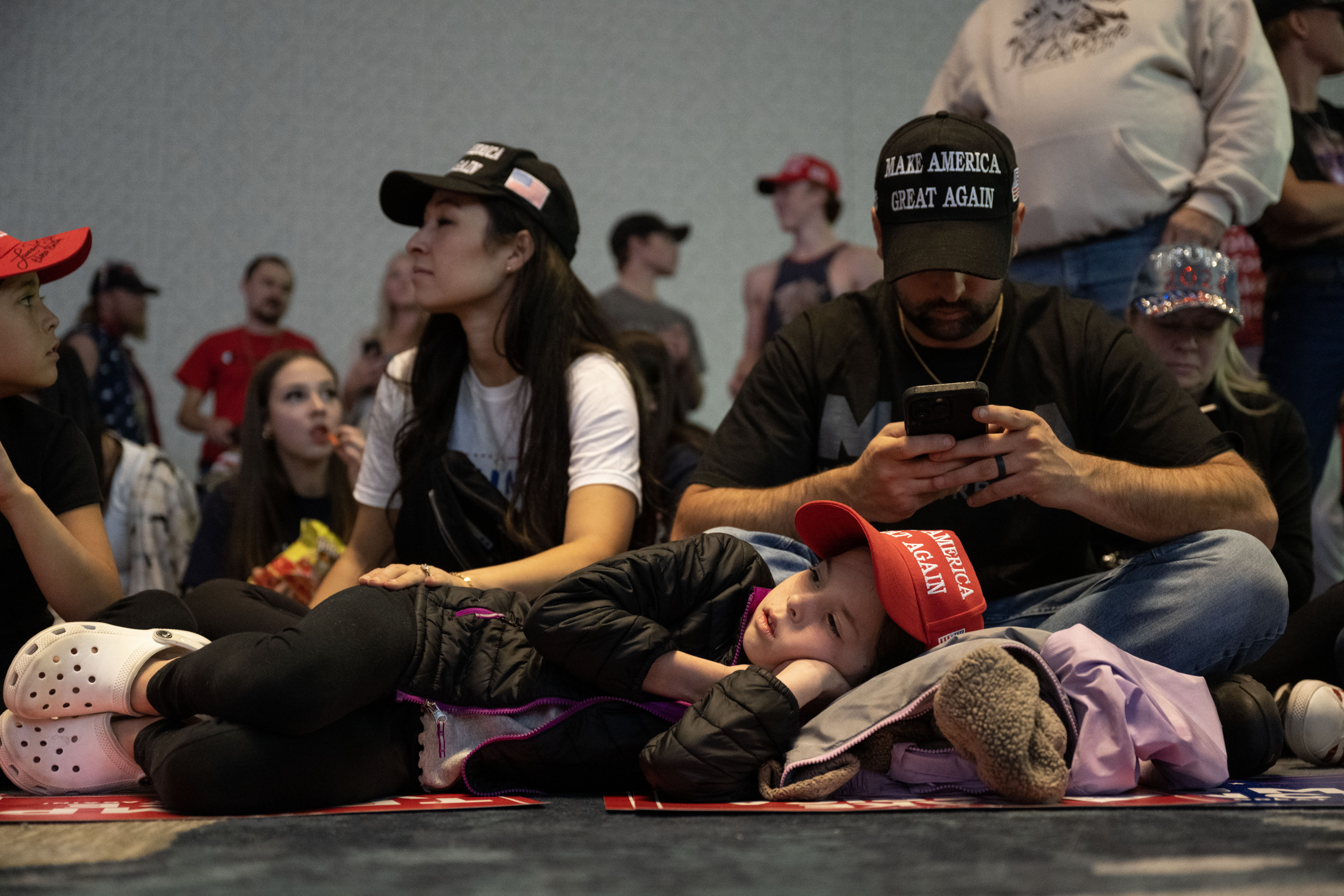 Meila Maree Dunlap, 8, lays on the floor with her sister Arabella, 10, and her parents Madelyn and Troy Dunlap as they wait for the start of a trump rally at the Gaylord Rockies Resort and Convention Center in Aurora on Friday, Oct. 11, 2024. (Stephen Swofford, Denver Gazette) (Stephen Swofford Denver Gazette)